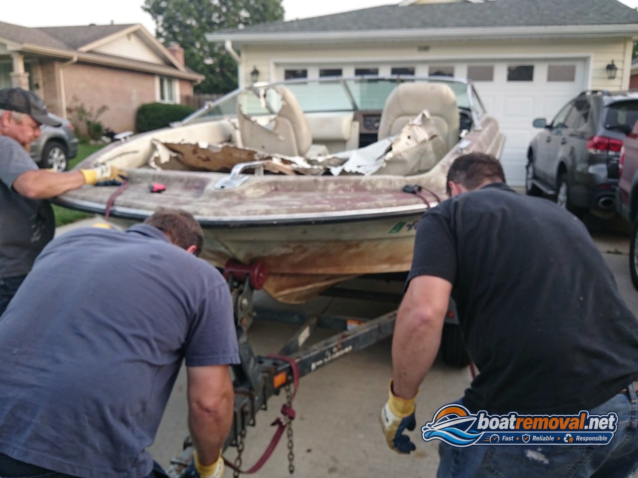 junk boat removal crew loading a 20 ft bowrider onto a trailer