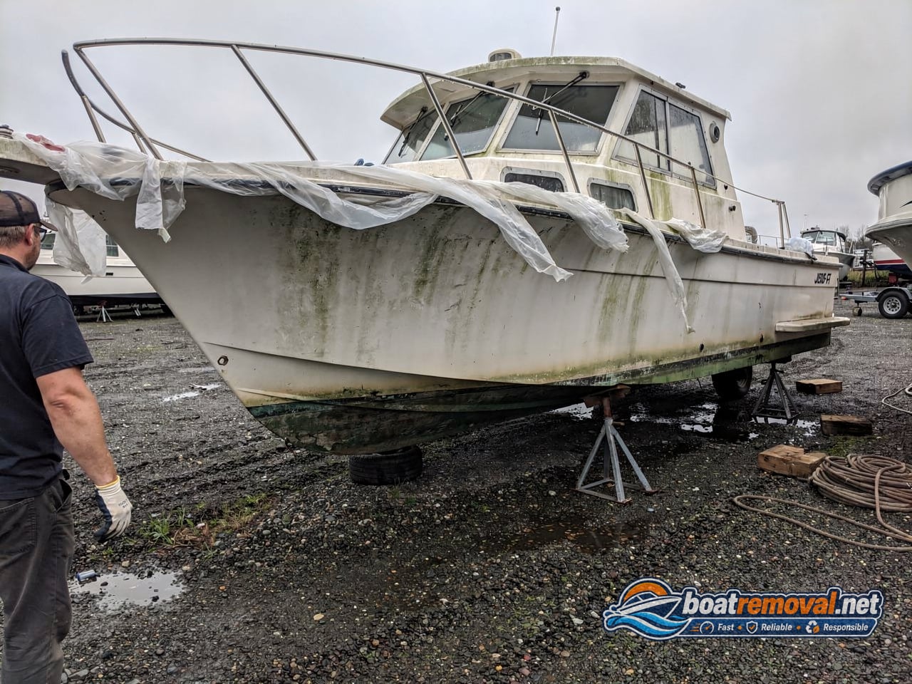 junk boat removal, 26 ft cabin cruiser on stands in a storage yard
