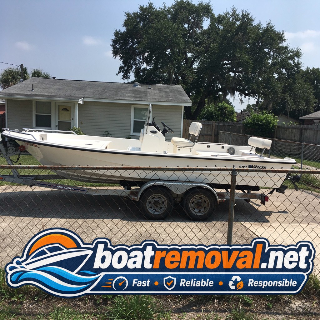 21-foot Boston Whaler center console sitting behind a chain-link fence in a Waveland, Mississippi yard