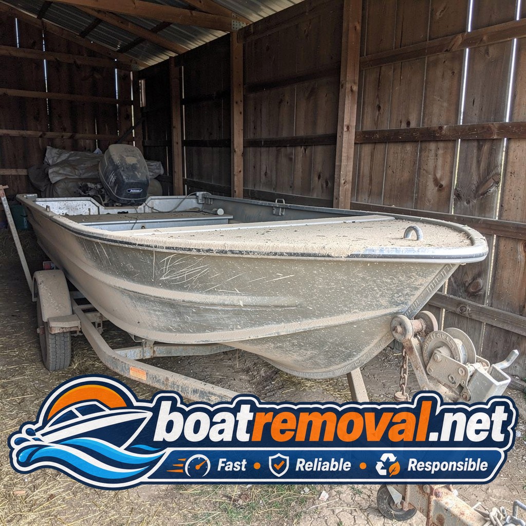 Small aluminum fishing boat covered in dust inside a barn