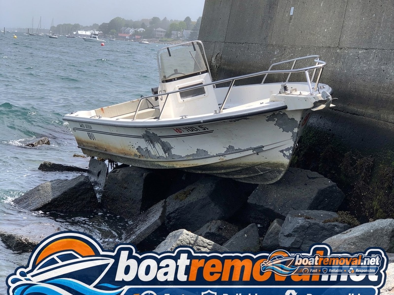 20-foot Grady-White center console wrecked on rocks below a seawall near Rockland, Maine