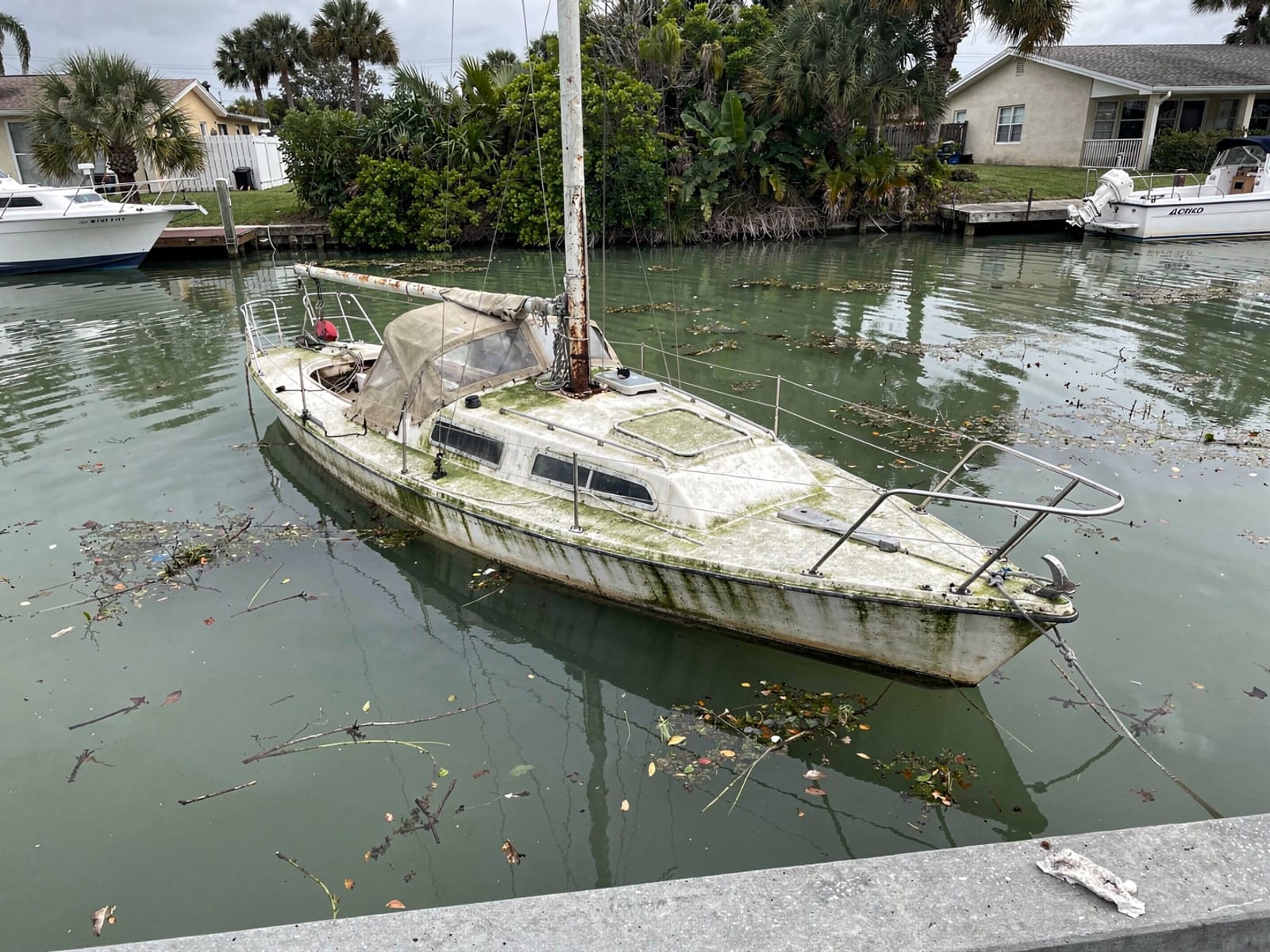 Sunken boat recovery in Citrus Park, FL: before Sunken 27 ft Cal 27 in a canal by the seawall in Citrus Park, FL