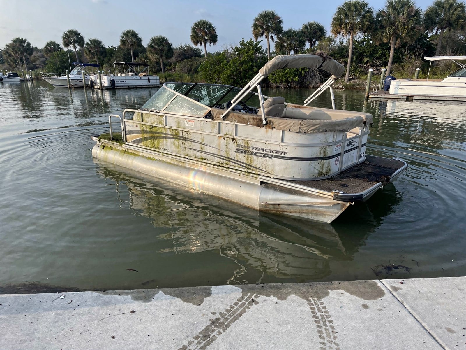 Sunken boat recovery in Clearwater, FL: before Sunken 22 ft Sun Tracker Party Barge 22 by a boat ramp in Clearwater, FL