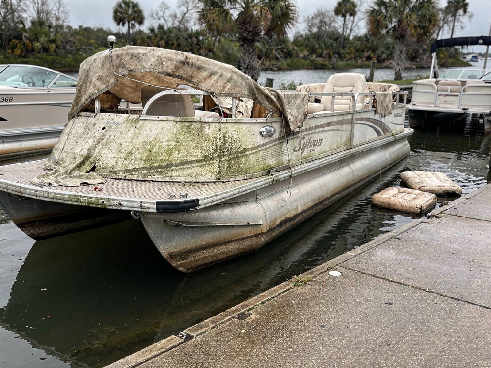 Sunken boat recovery in Coral Gables, FL: before Sunken 20 ft Sylvan Mirage 20 by a boat ramp in Coral Gables, FL
