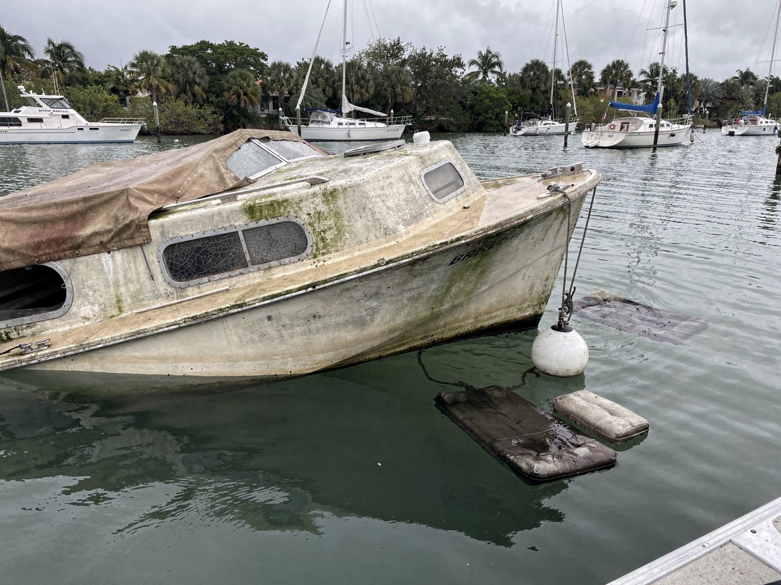 Sunken boat recovery in Coral Terrace, FL: before Sunken 27 ft Ericson 27 at its mooring in Coral Terrace, FL