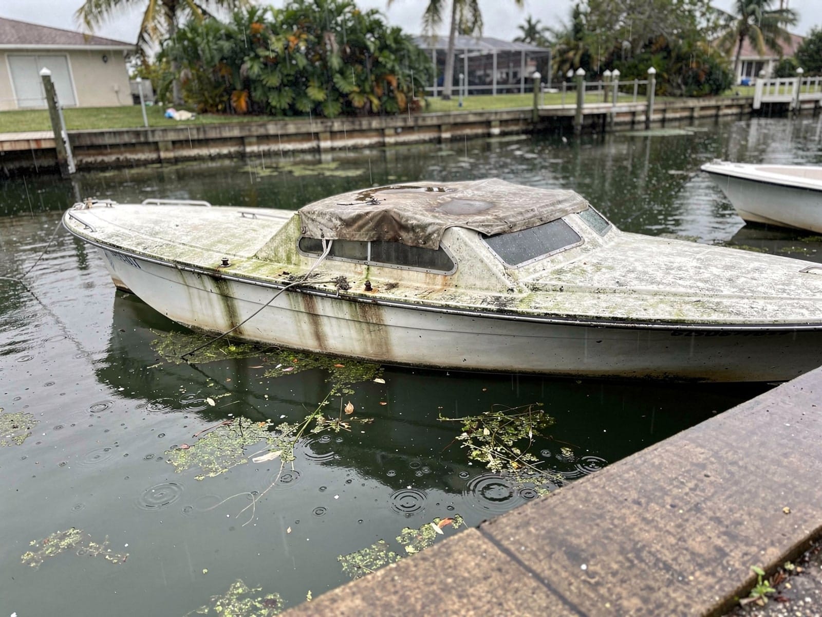 Sunken boat recovery in Delray Beach, FL: before Sunken 25 ft O'Day 25 in a canal by the seawall in Delray Beach, FL
