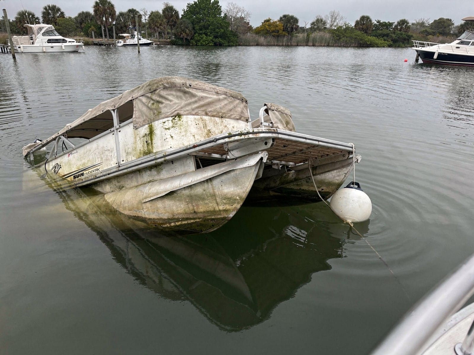 Sunken boat recovery in Fort Pierce, FL: before Sunken 22 ft Sun Tracker Party Barge 22 at its mooring in Fort Pierce, FL