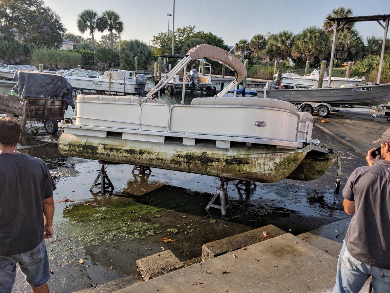 Sunken boat recovery in Gainesville, FL: at the repair yard 24 ft Harris FloteBote 24 from Gainesville, FL on stands at a repair yard after the recovery