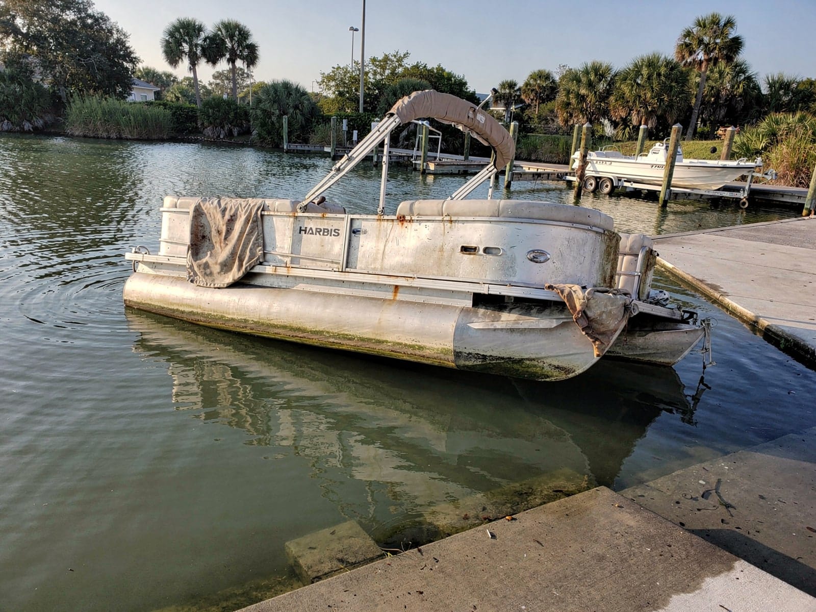 Sunken boat recovery in Gainesville, FL: before Sunken 24 ft Harris FloteBote 24 by a boat ramp in Gainesville, FL