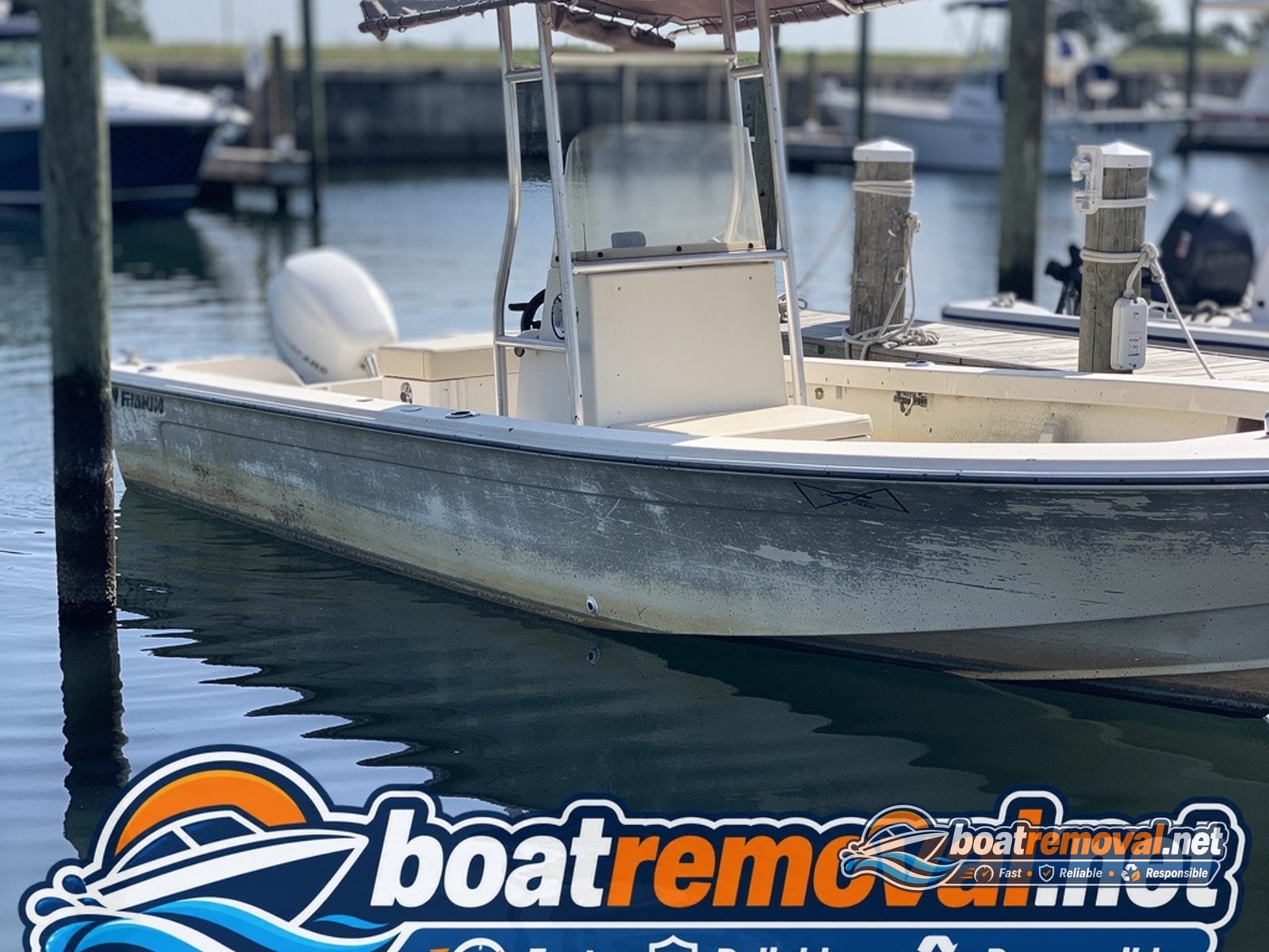 Center console fishing boat with faded gelcoat tied up in a marina slip