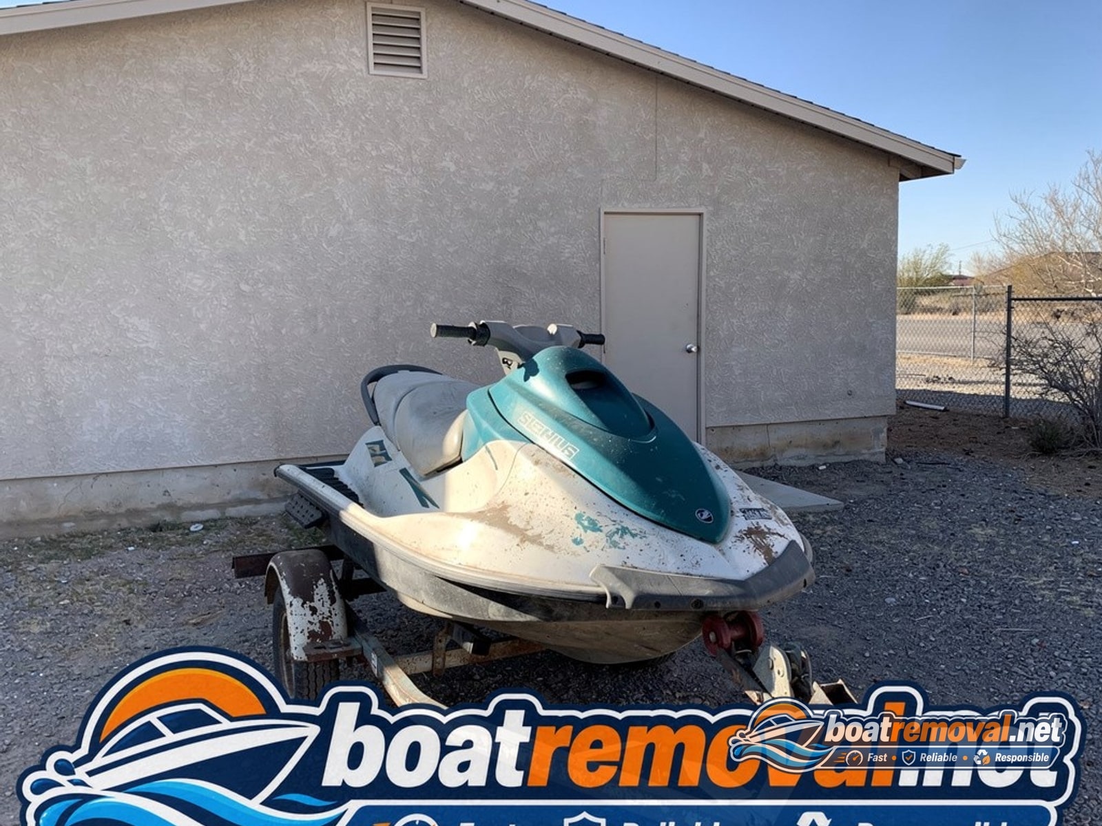 Two-seat jet ski on a rusted trailer behind a garage in Henderson, Nevada before pickup