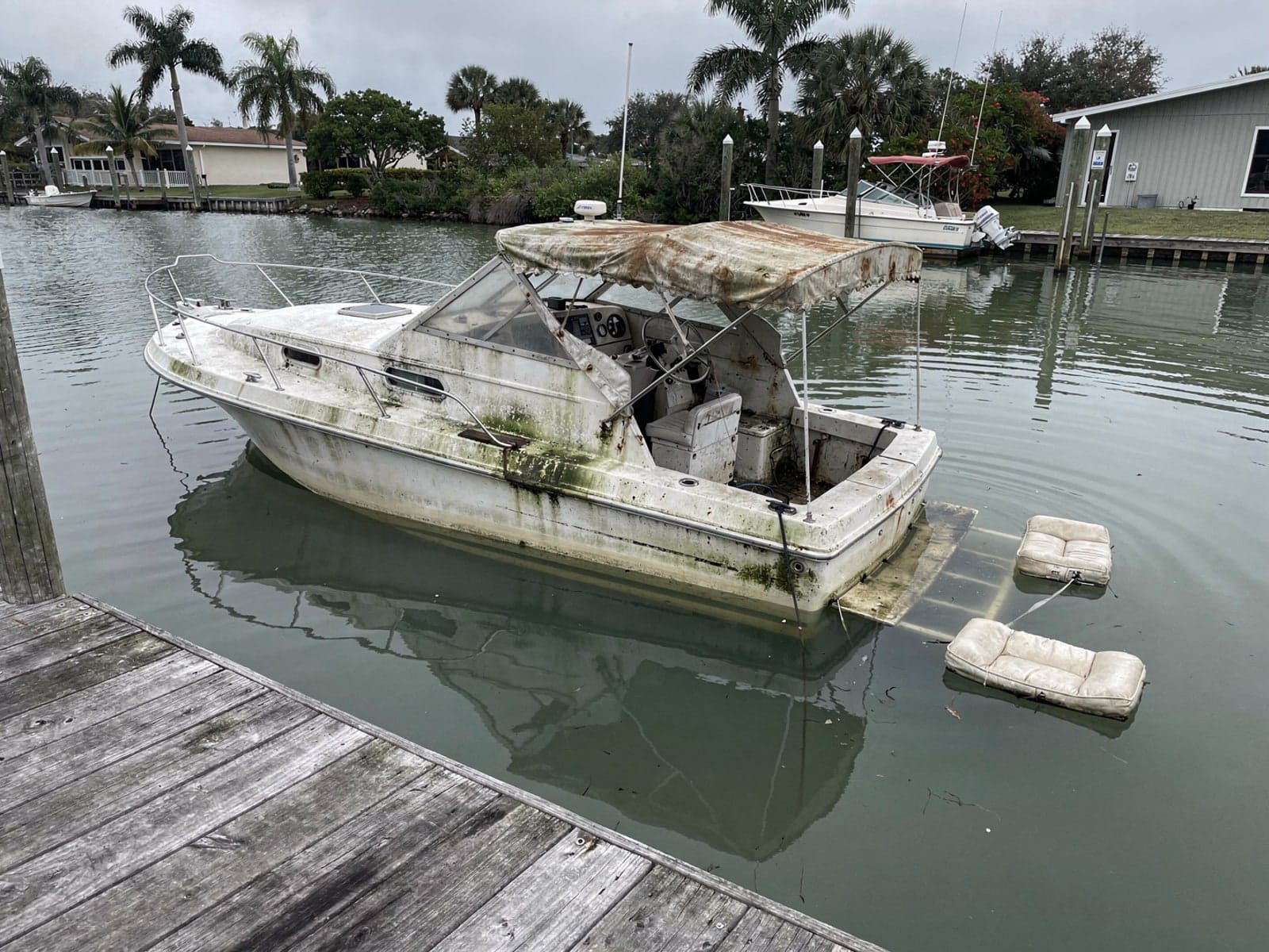 Sunken boat recovery in Horizon West, FL: before Sunken 28 ft Bertram 28 at a lake dock in Horizon West, FL