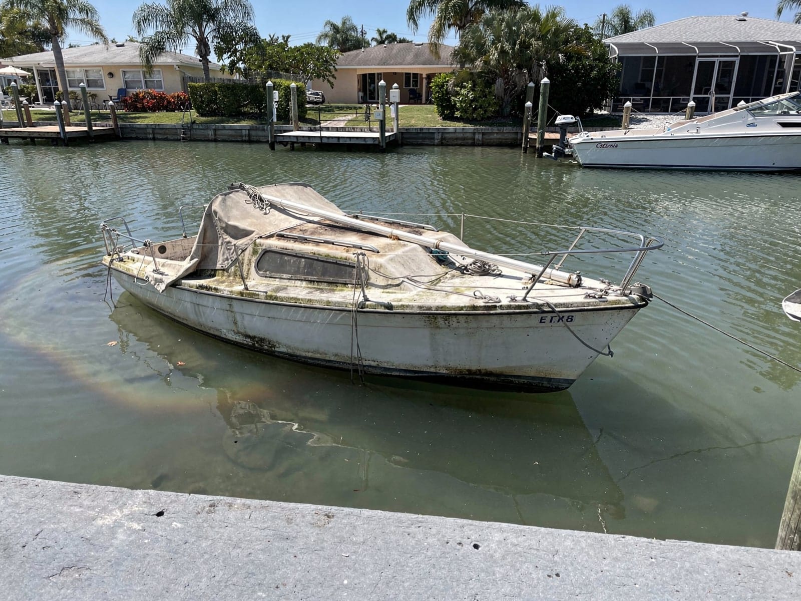 Sunken boat recovery in Jacksonville Beach, FL: before Sunken 22 ft Catalina 22 in a canal by the seawall in Jacksonville Beach, FL