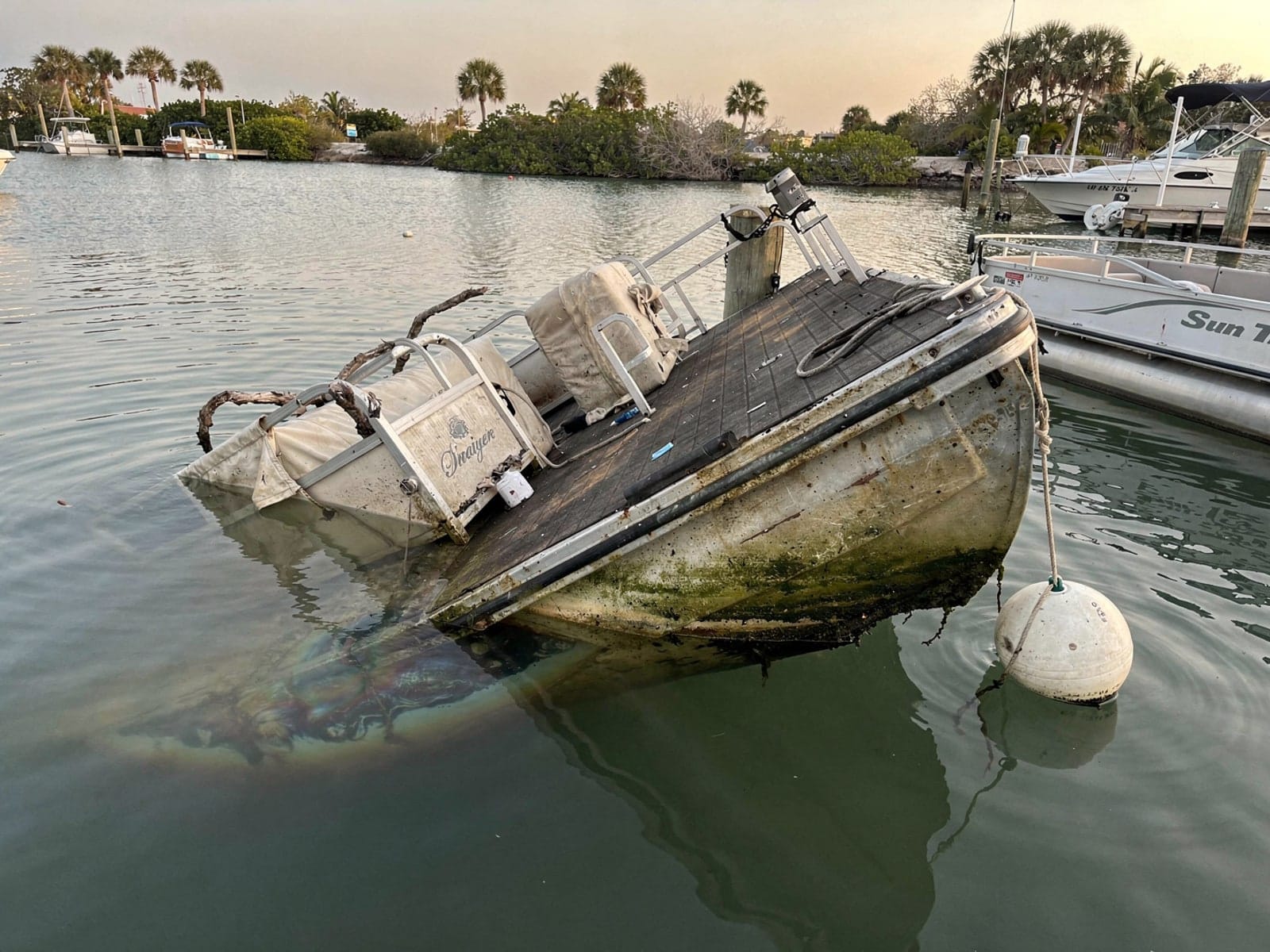 Sunken boat recovery in Jupiter Farms, FL: before Sunken 22 ft Sun Tracker Party Barge 22 at its mooring in Jupiter Farms, FL