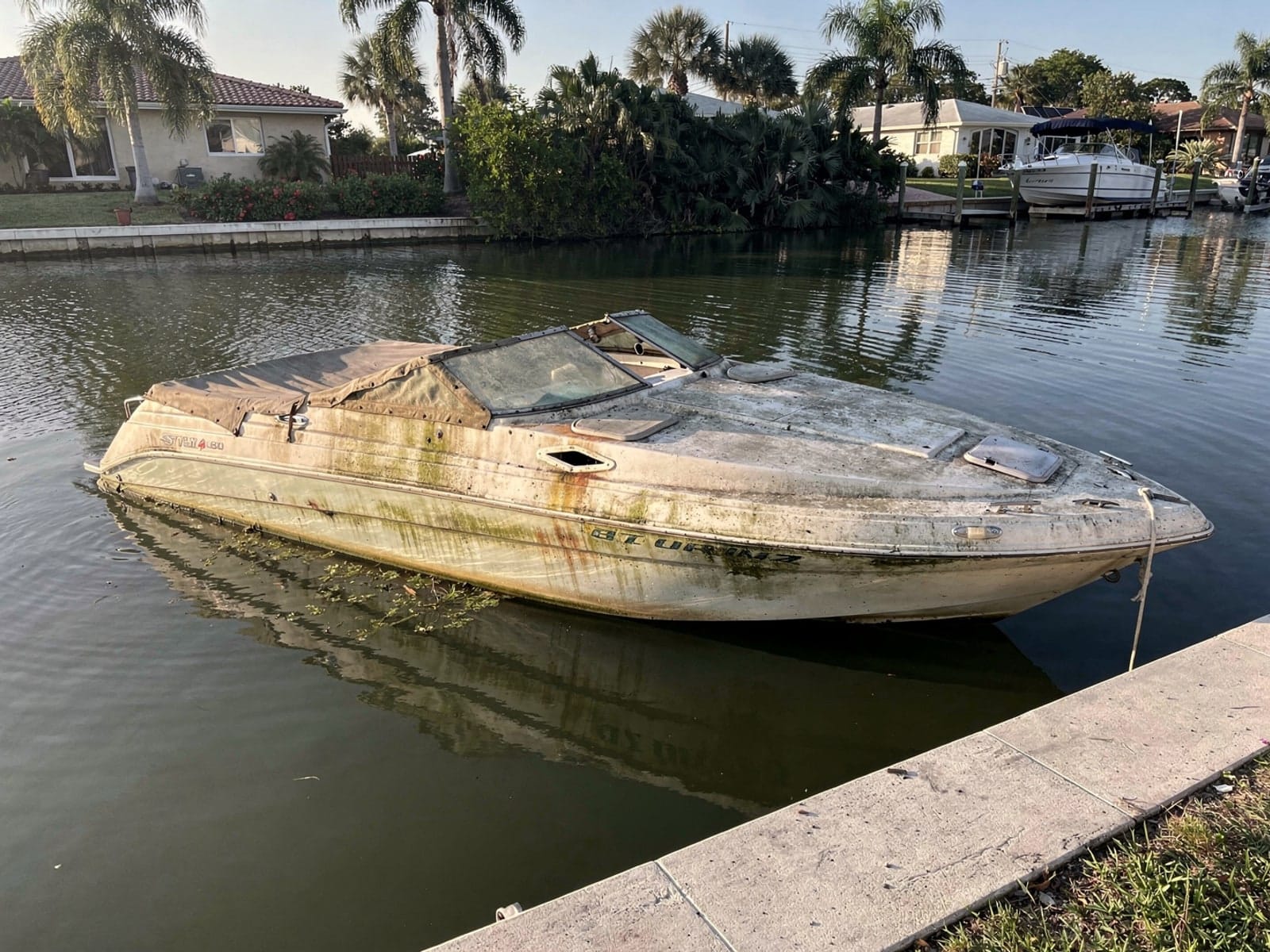 Sunken boat recovery in Kendale Lakes, FL: before Sunken 24 ft Formula 242 in a canal by the seawall in Kendale Lakes, FL