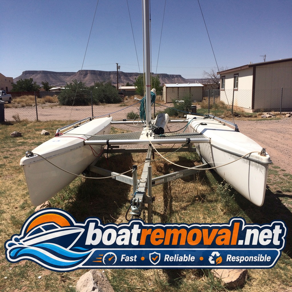 19-foot Hobie catamaran sailboat on a trailer in a Las Cruces, New Mexico yard before removal