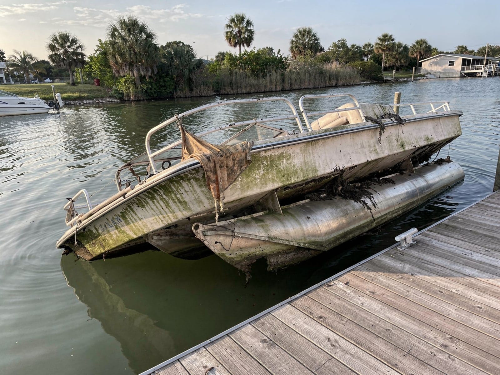 Sunken boat recovery in Lauderdale Lakes, FL: before Sunken 20 ft Sylvan Mirage 20 at a lake dock in Lauderdale Lakes, FL