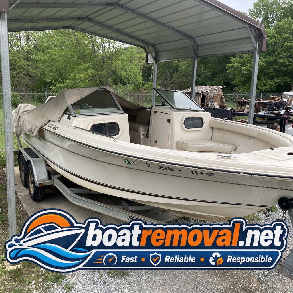 Fiberglass cuddy cabin boat on a trailer under a carport, faded canvas cover half off