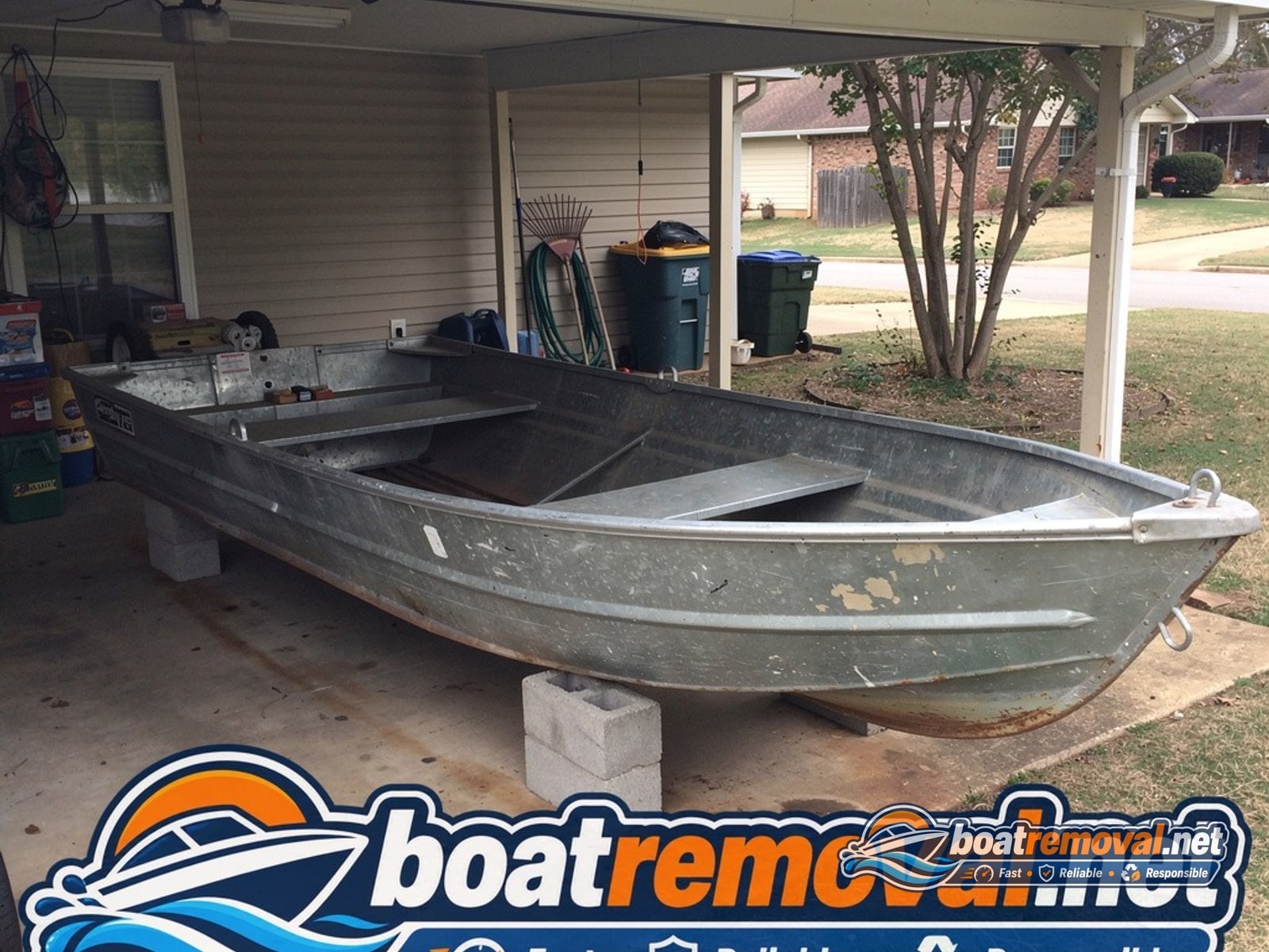 16-foot Grumman aluminum boat resting on blocks under a low carport in Little Rock, Arkansas