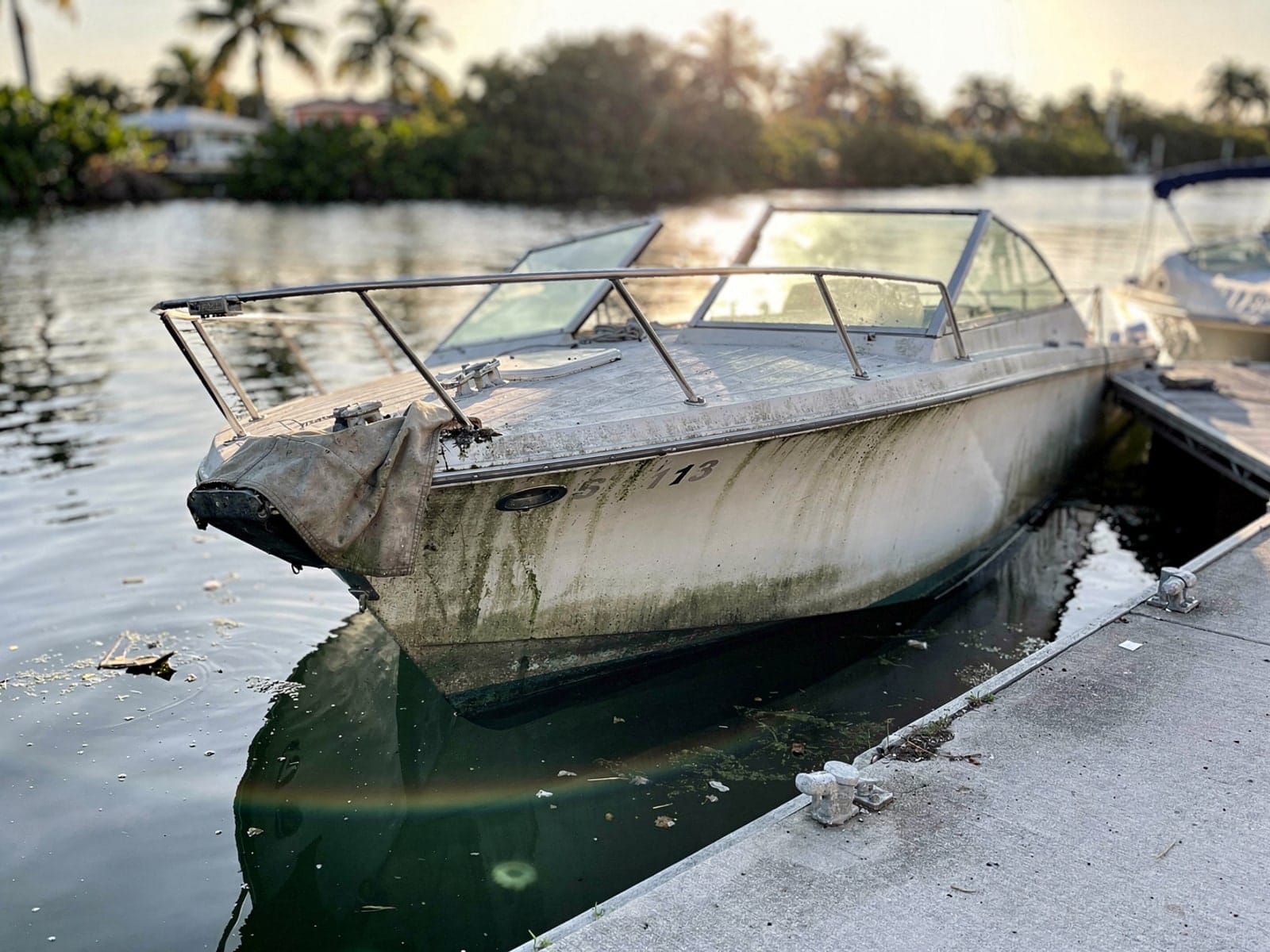 Sunken boat recovery in Hobe Sound, FL: before Sunken 27 ft Chris-Craft Commander 27 by a boat ramp in Hobe Sound, FL