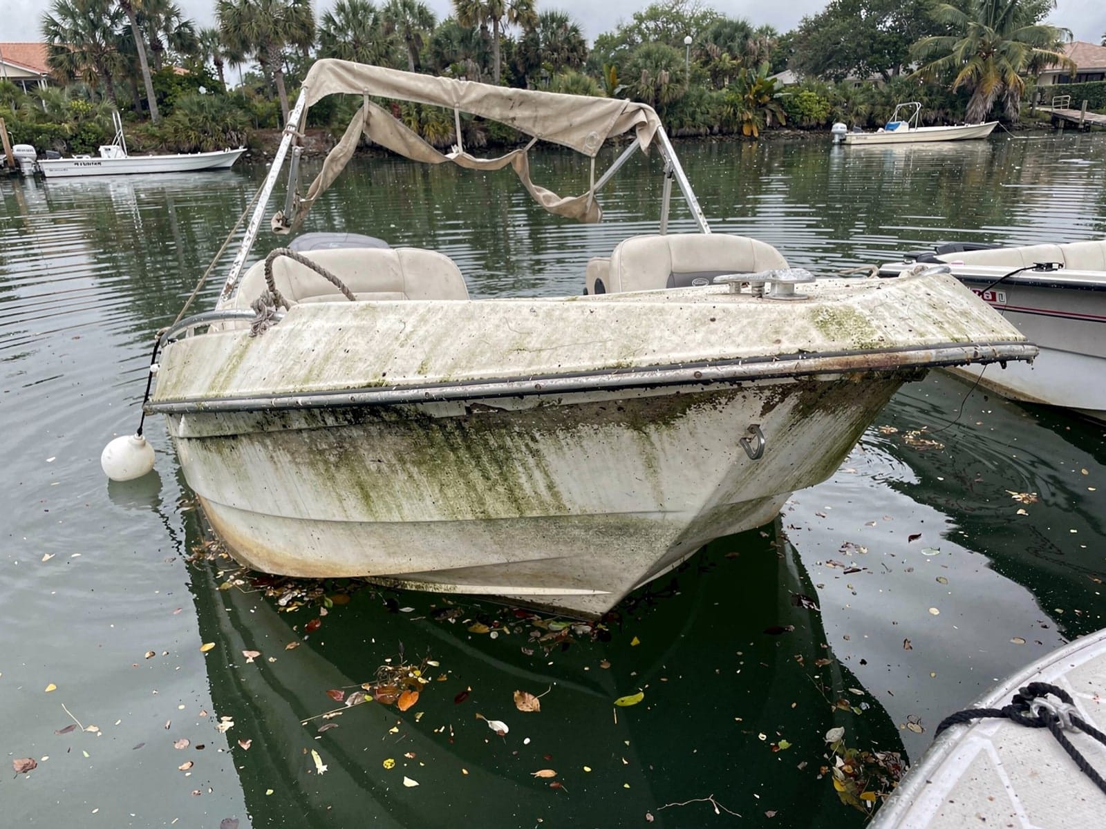 Sunken boat recovery in Naples, FL: before Sunken 24 ft Harris FloteBote 24 at its mooring in Naples, FL