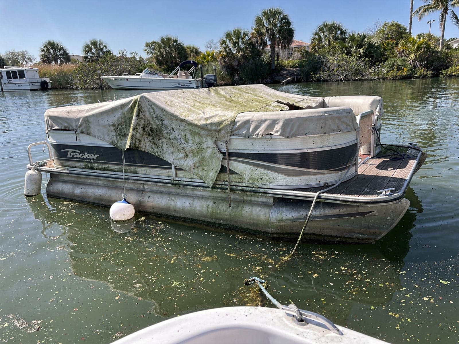 Sunken boat recovery in Northdale, FL: before Sunken 22 ft Sun Tracker Party Barge 22 at its mooring in Northdale, FL