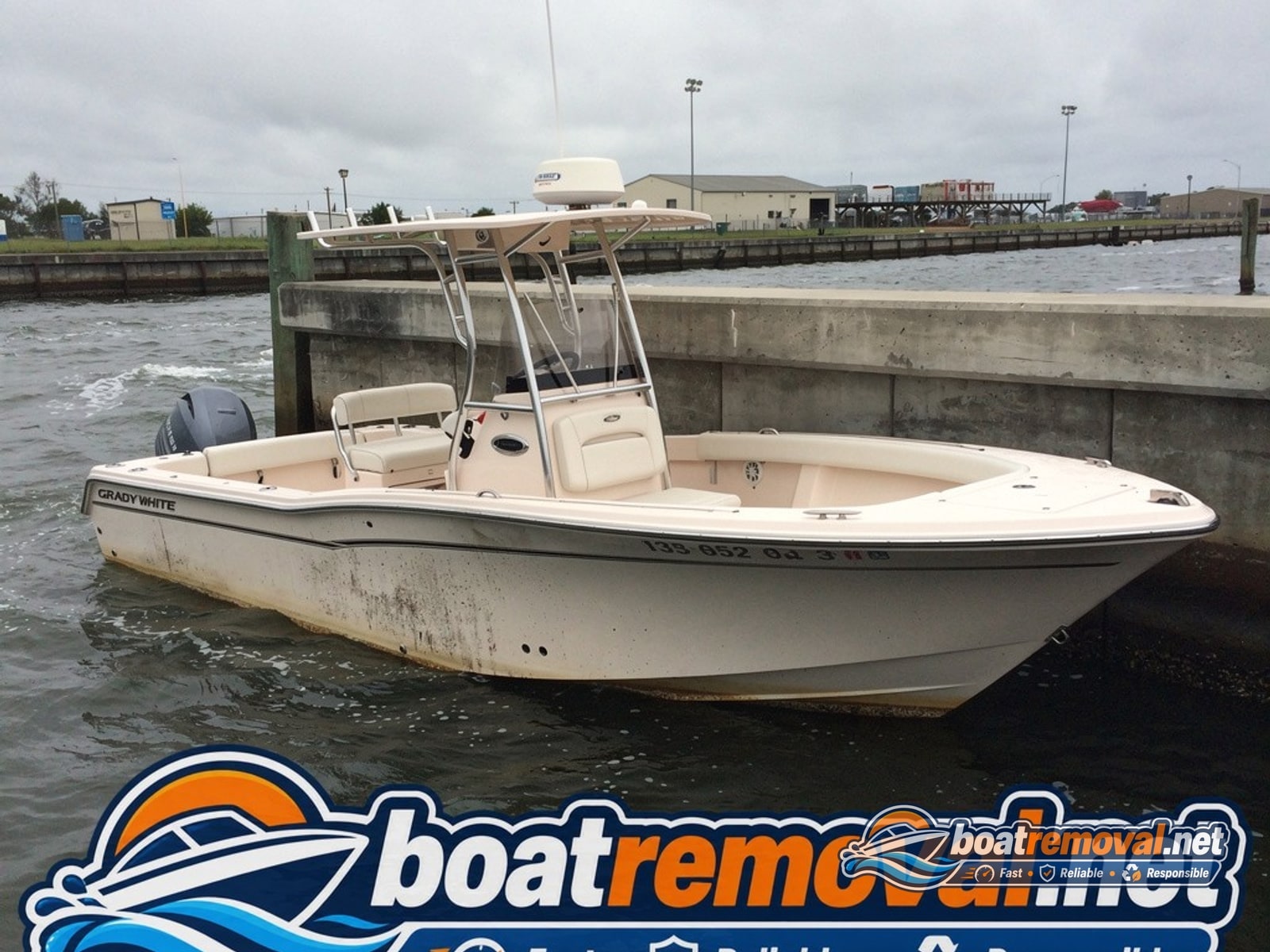 23-foot Grady-White center console listing against a seawall in Pascagoula, Mississippi after storm damage