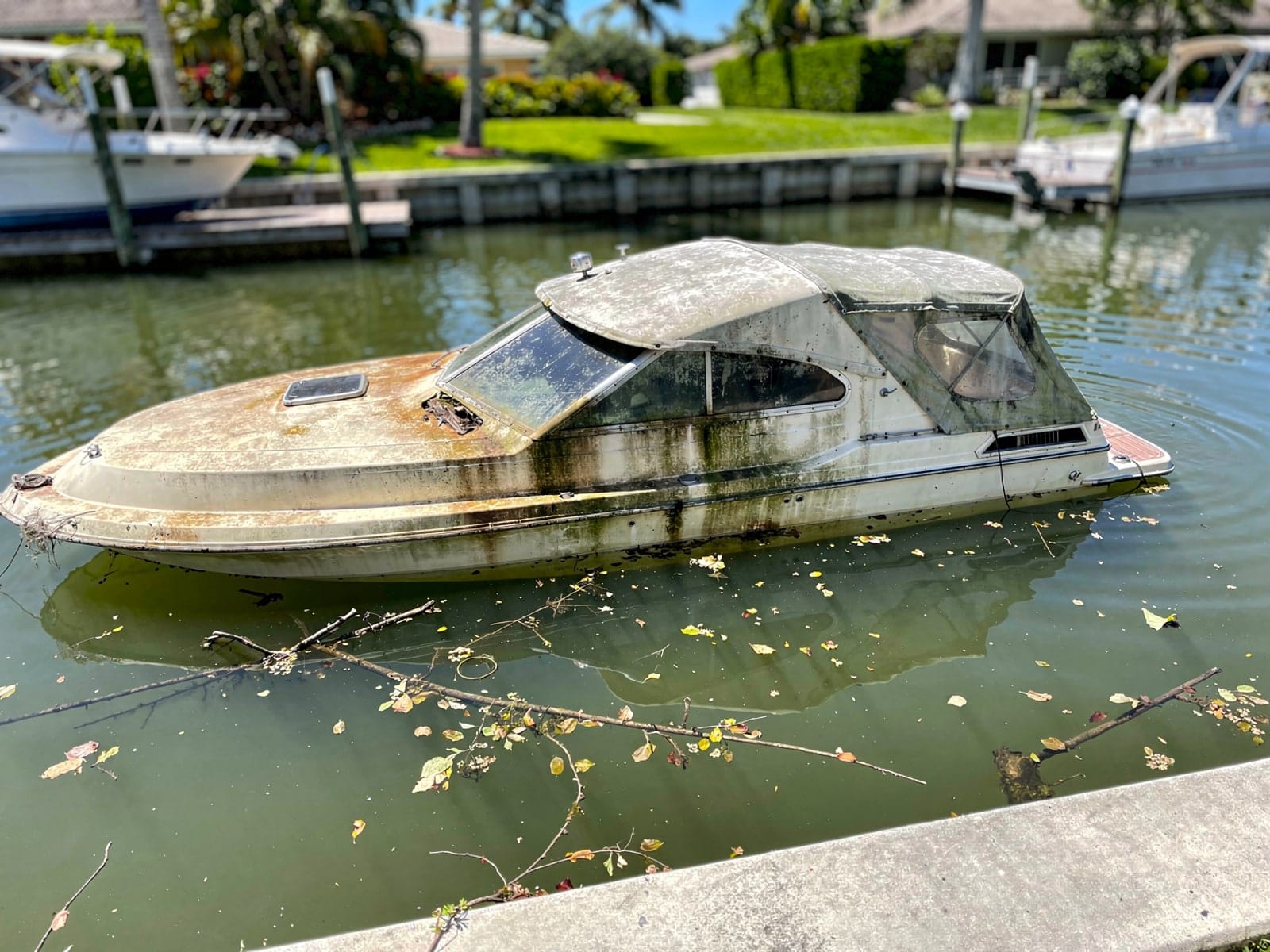 Sunken boat recovery in Plant City, FL: before Sunken 28 ft Carver 28 in a canal by the seawall in Plant City, FL
