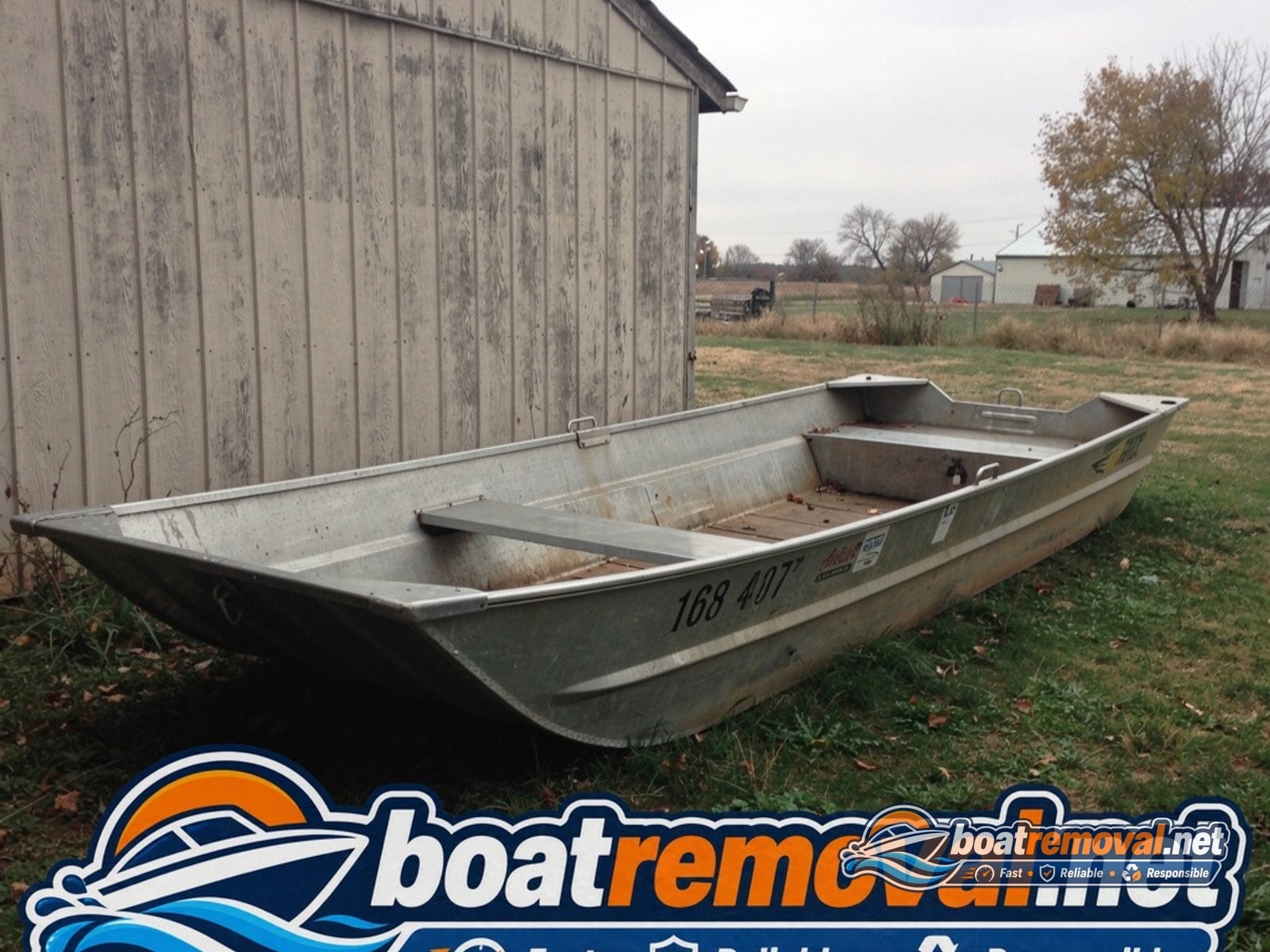 16-foot aluminum jon boat resting behind a shed near Plattsmouth, Nebraska before removal