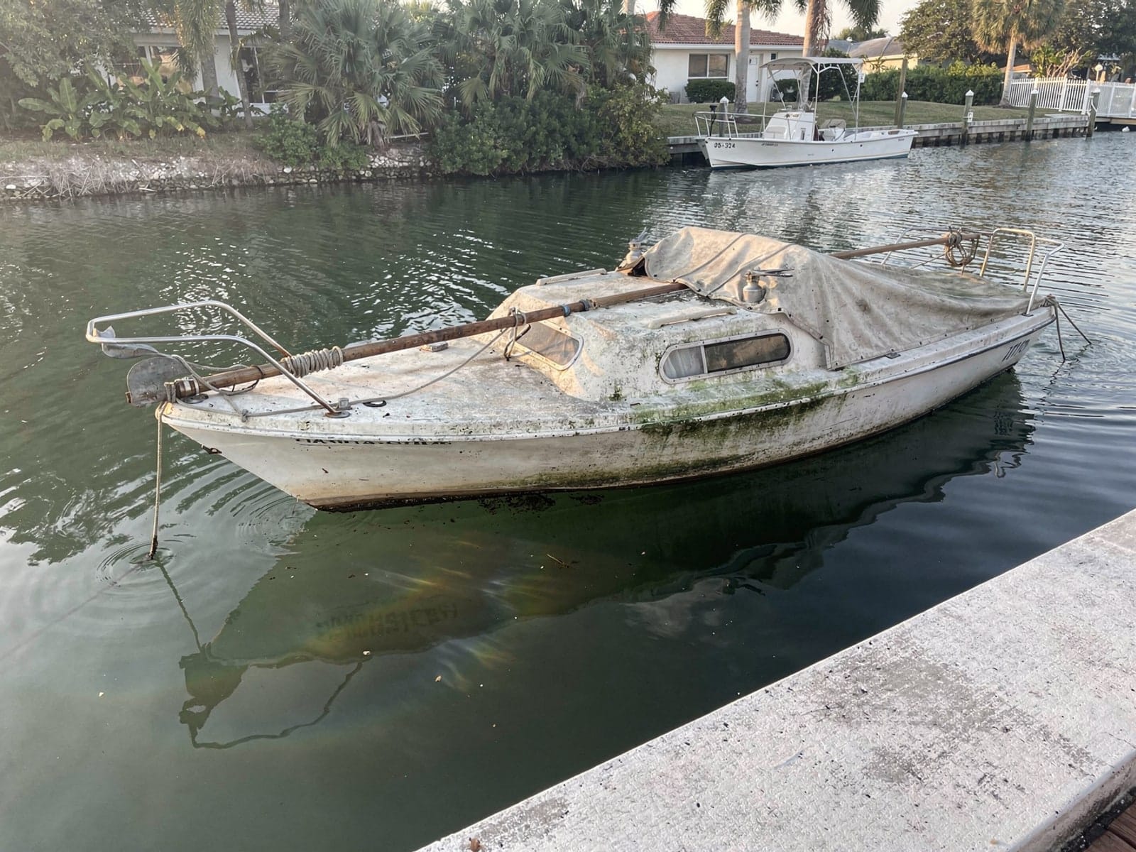 Sunken boat recovery in South Bradenton, FL: before Sunken 22 ft Catalina 22 in a canal by the seawall in South Bradenton, FL