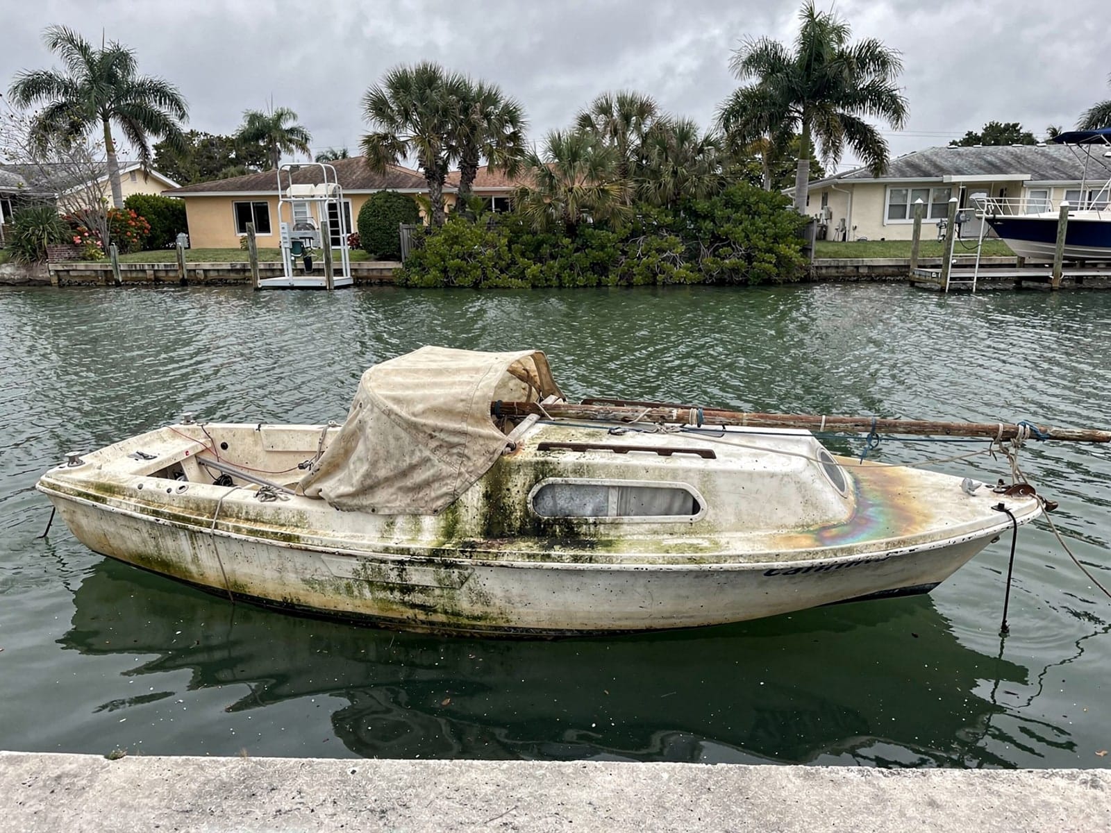 Sunken boat recovery in Apollo Beach, FL: before Sunken 22 ft Catalina 22 in a canal by the seawall in Apollo Beach, FL