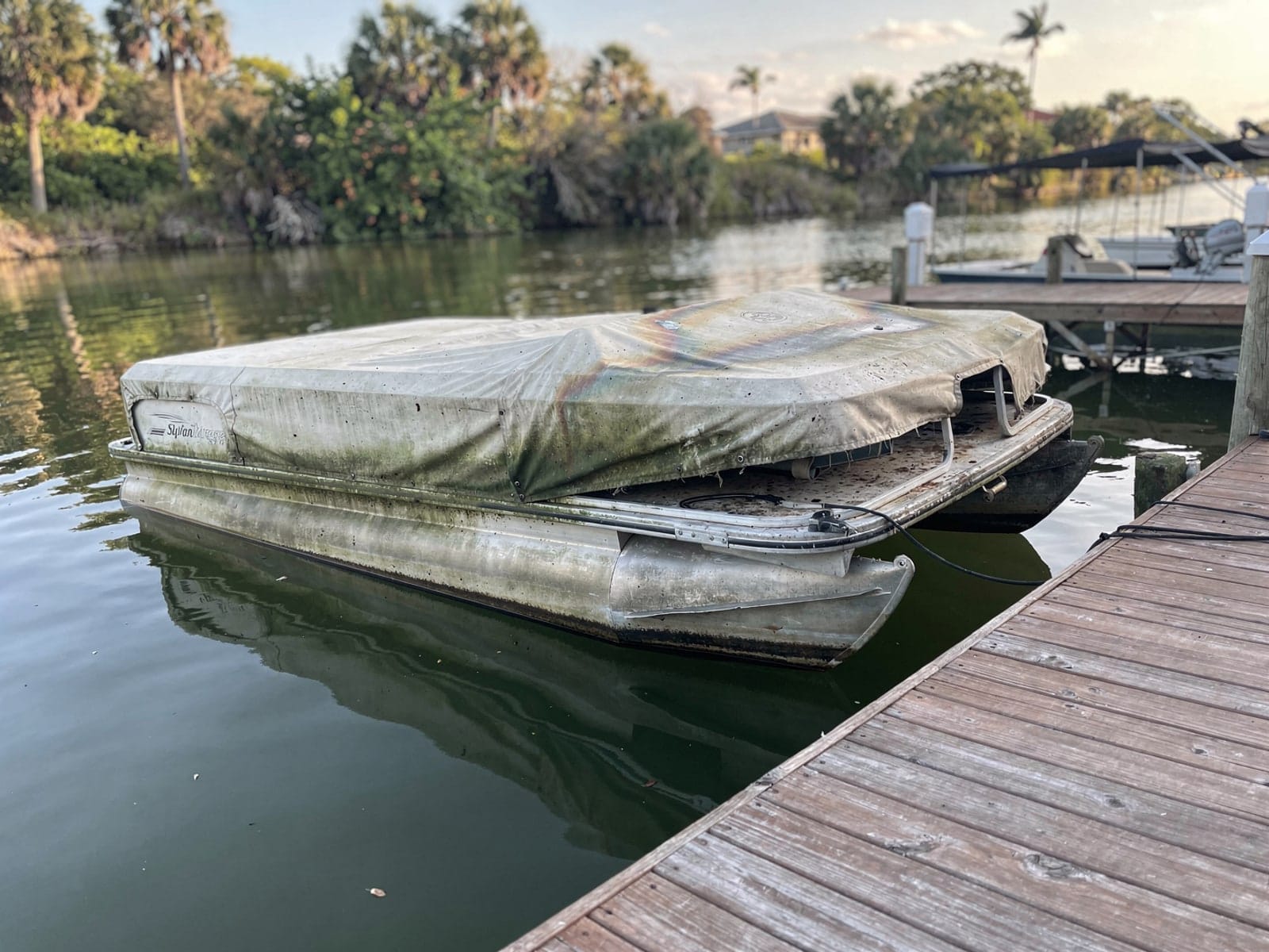 Sunken boat recovery in Eustis, FL: before Sunken 20 ft Sylvan Mirage 20 at a lake dock in Eustis, FL