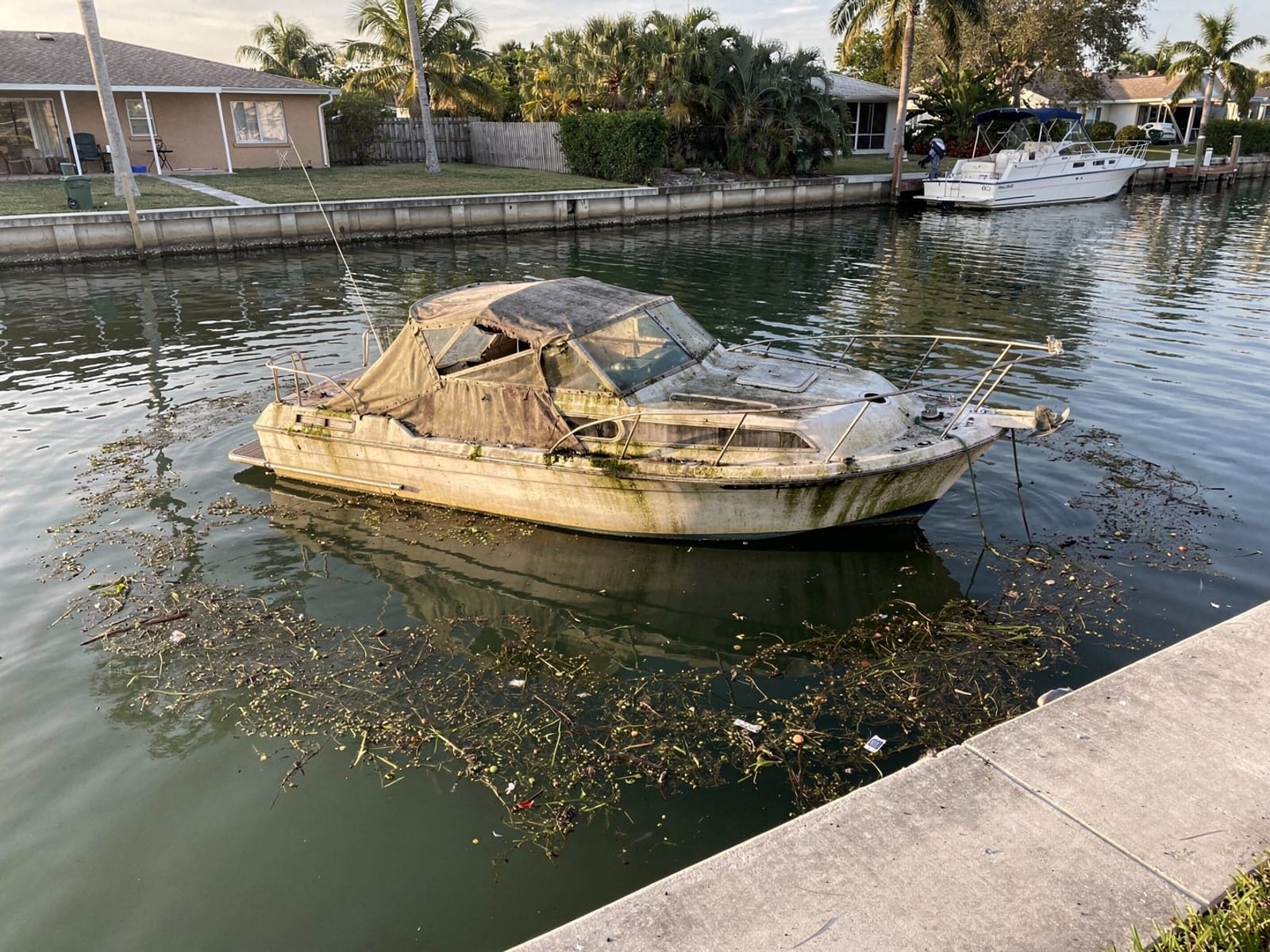 Sunken 27 ft Chris-Craft Commander 27 in a canal by the seawall in Town N Country, FL
