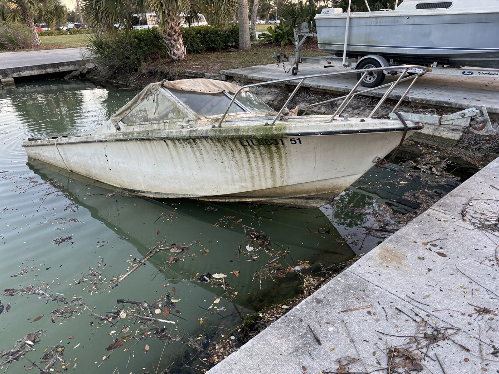 Sunken boat recovery in Sun City Center, FL: before Sunken 21 ft Thompson 21 by a boat ramp in Sun City Center, FL
