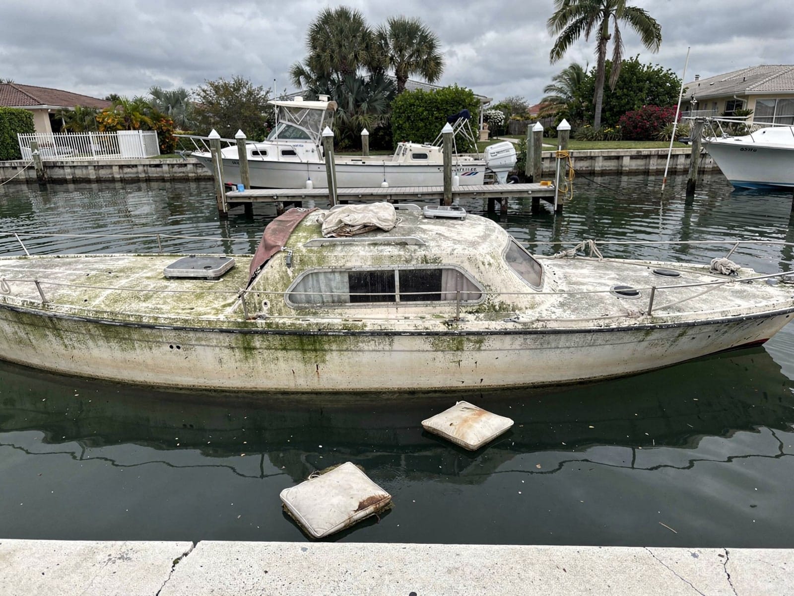 Sunken boat recovery in Bonita Springs, FL: before Sunken 26 ft Pearson 26 in a canal by the seawall in Bonita Springs, FL