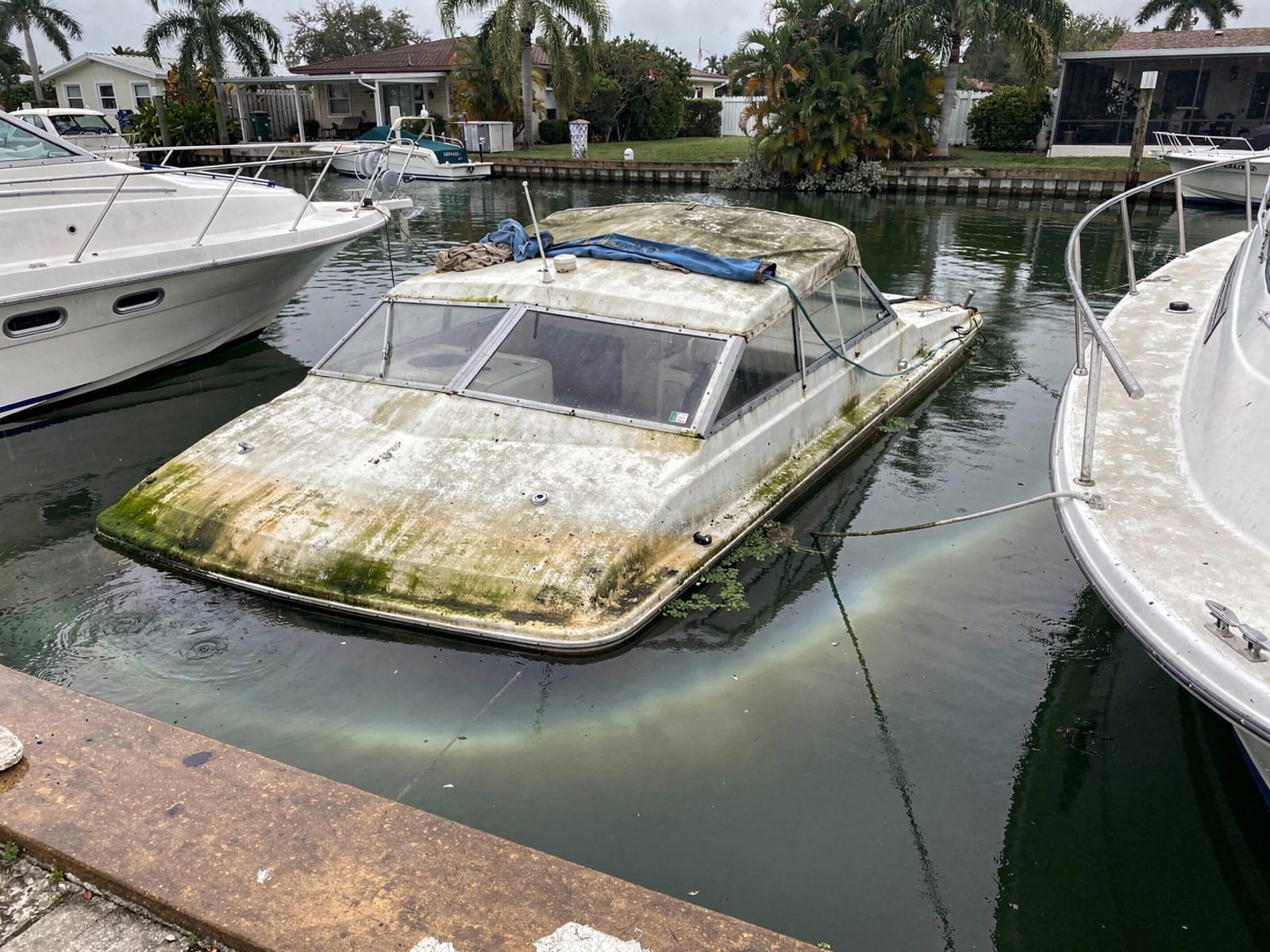 Sunken boat recovery in Palm Valley, FL: before Sunken 34 ft Silverton 34 in a canal by the seawall in Palm Valley, FL