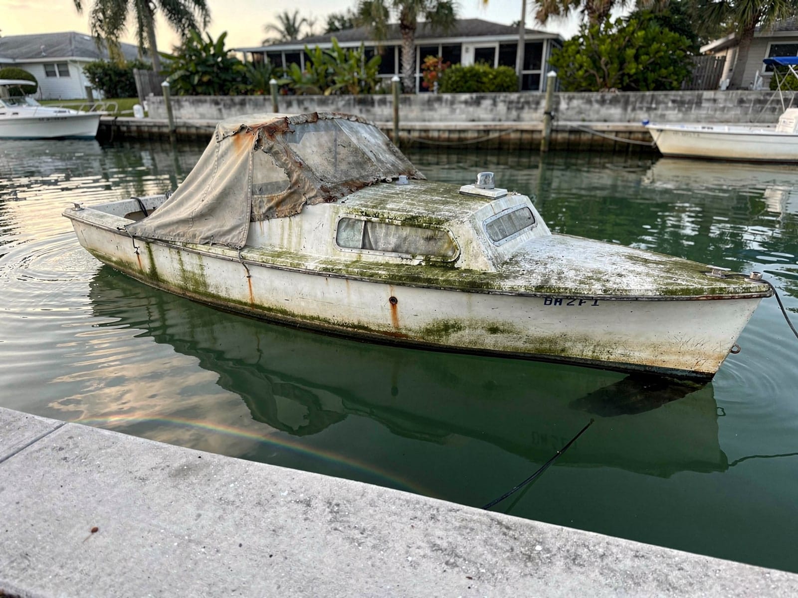 Sunken boat recovery in South Miami Heights, FL: before Sunken 25 ft O'Day 25 in a canal by the seawall in South Miami Heights, FL