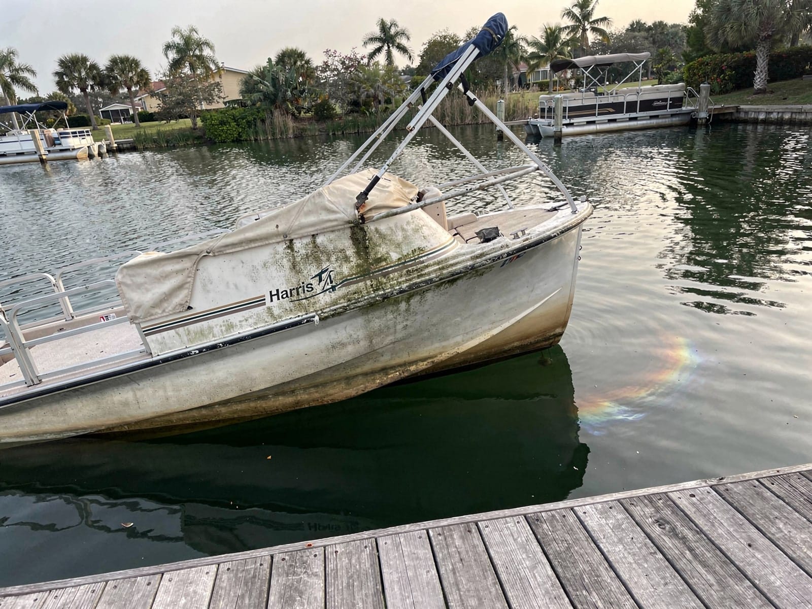 Sunken boat recovery in Callaway, FL: before Sunken 24 ft Harris FloteBote 24 at a lake dock in Callaway, FL
