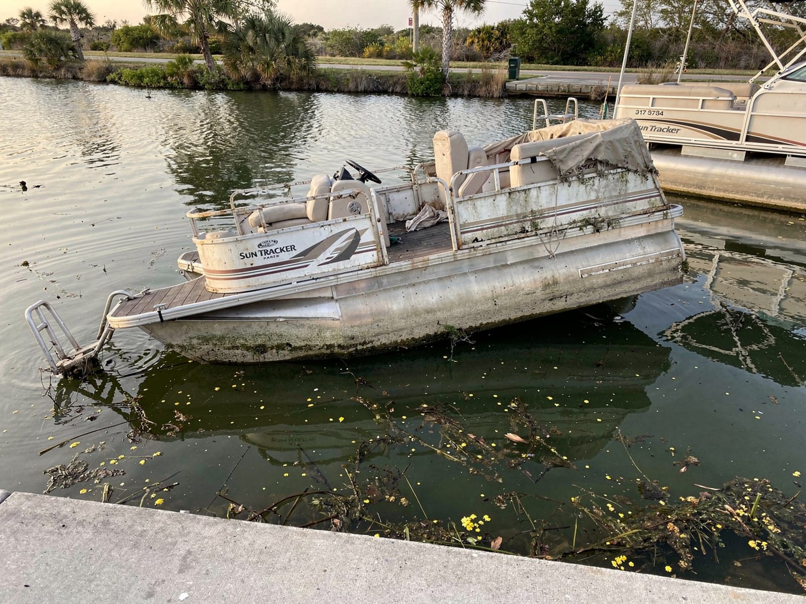 Sunken boat recovery in Doral, FL: before Sunken 22 ft Sun Tracker Party Barge 22 by a boat ramp in Doral, FL