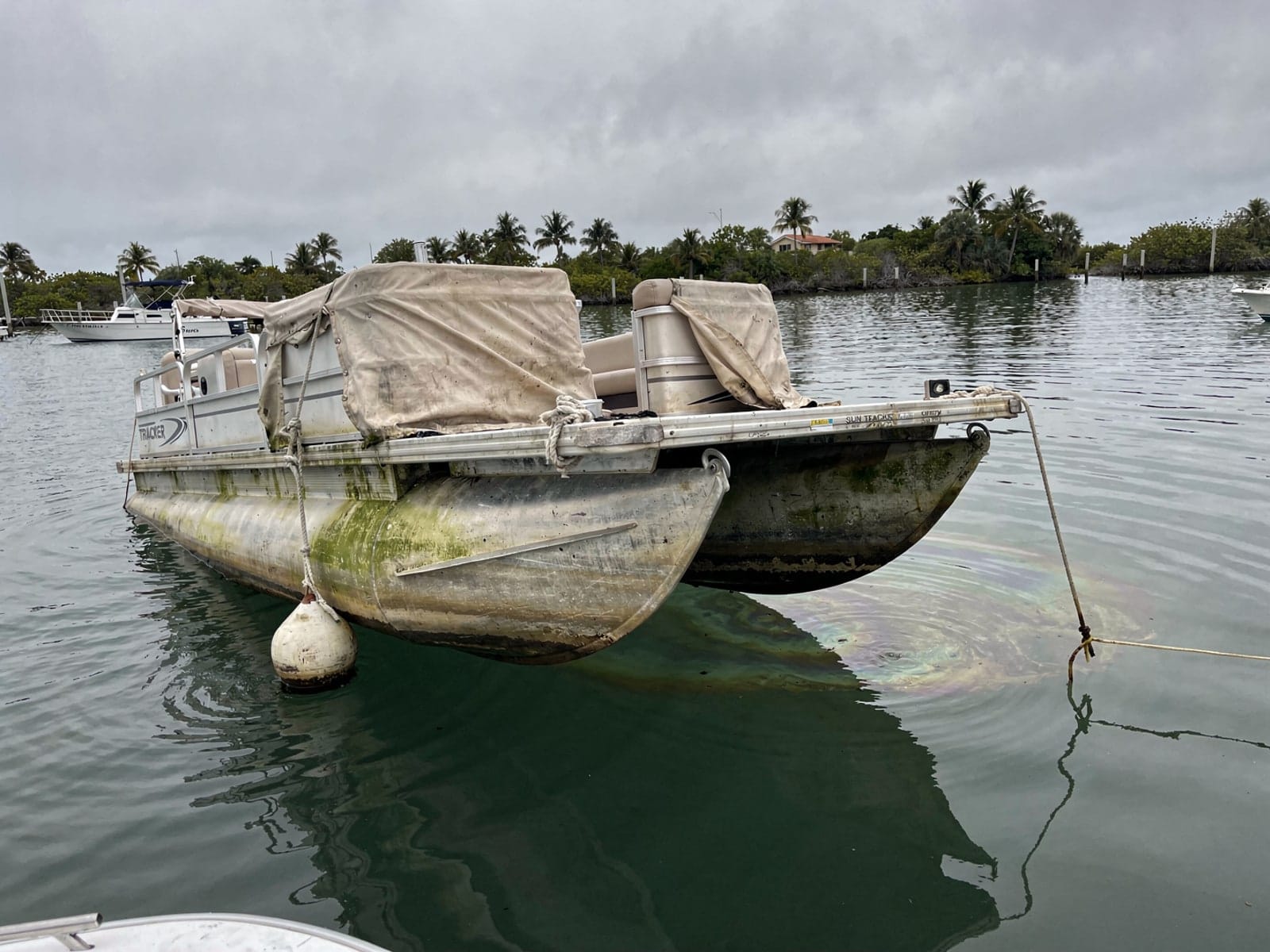 Sunken boat recovery in Edgewater, FL: before Sunken 22 ft Sun Tracker Party Barge 22 at its mooring in Edgewater, FL