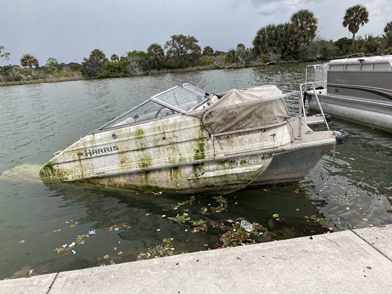 Sunken boat recovery in Jupiter, FL: before Sunken 24 ft Harris FloteBote 24 by a boat ramp in Jupiter, FL
