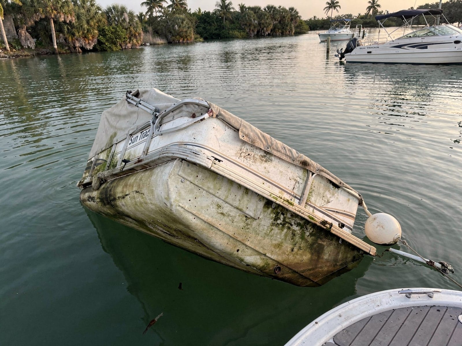 Sunken boat recovery in Ruskin, FL: before Sunken 22 ft Sun Tracker Party Barge 22 at its mooring in Ruskin, FL