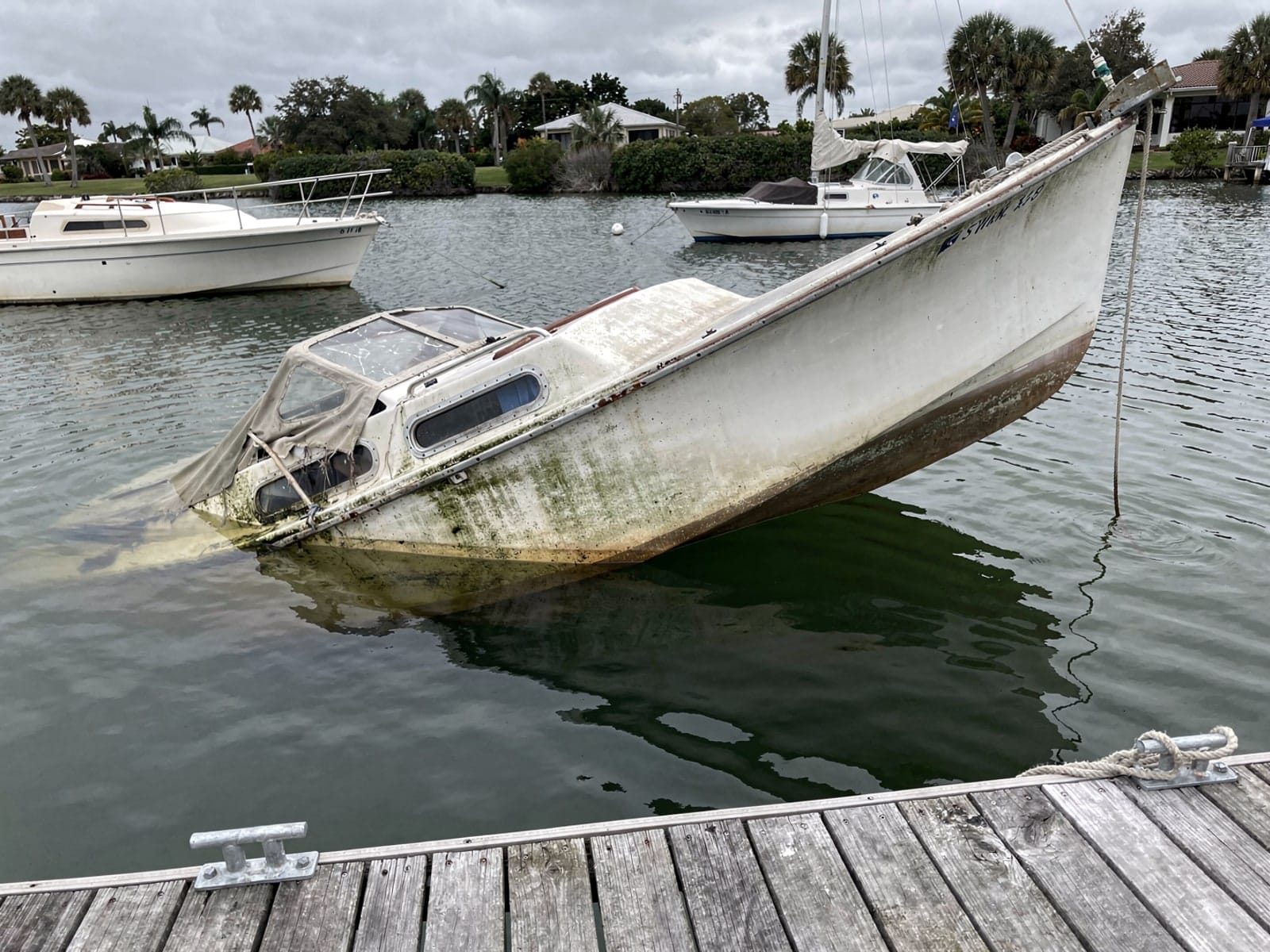 Sunken boat recovery in Carrollwood, FL: before Sunken 27 ft Ericson 27 at a lake dock in Carrollwood, FL