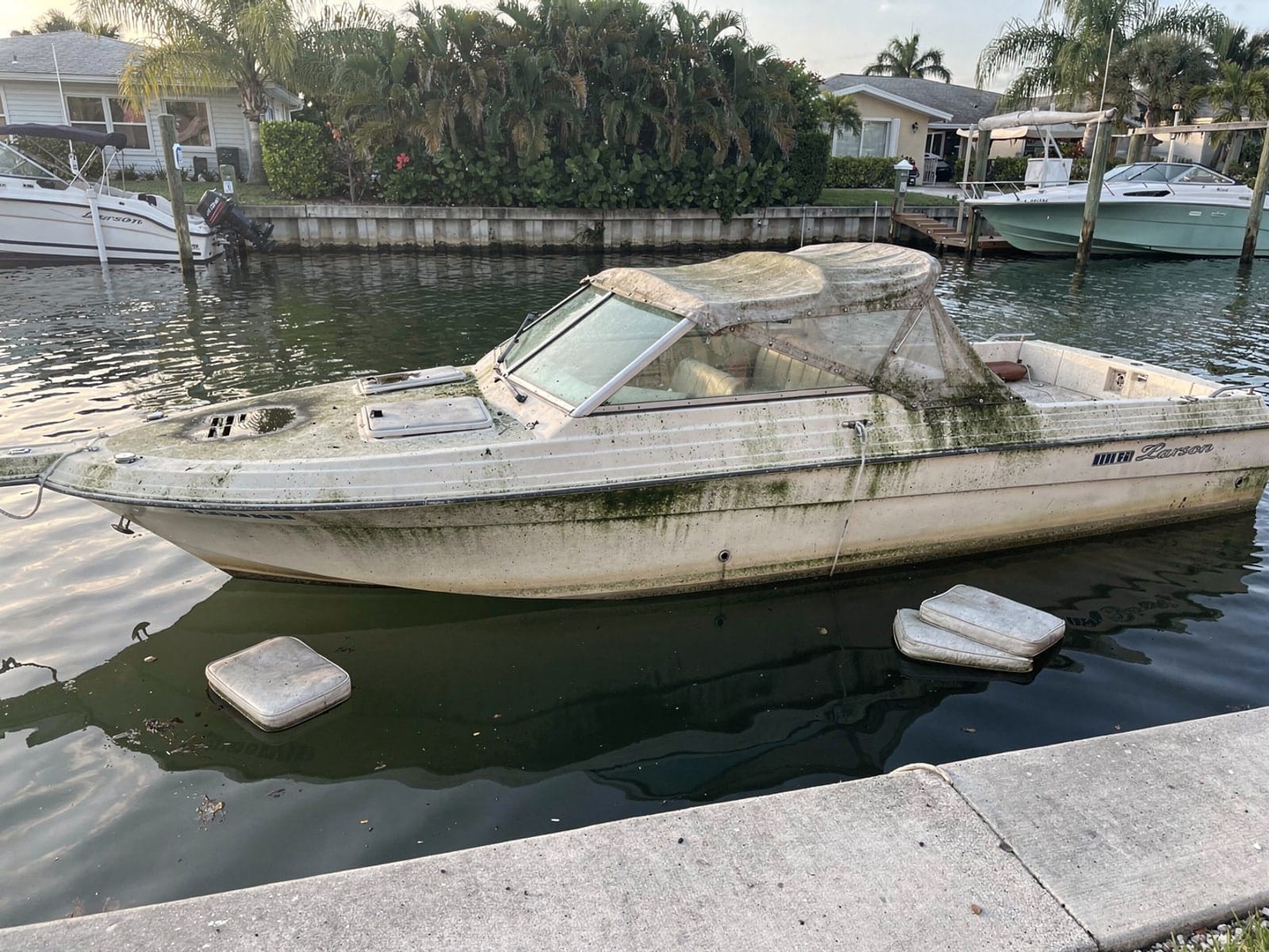 Sunken boat recovery in Spring Hill, FL: before Sunken 22 ft Larson 220 in a canal by the seawall in Spring Hill, FL