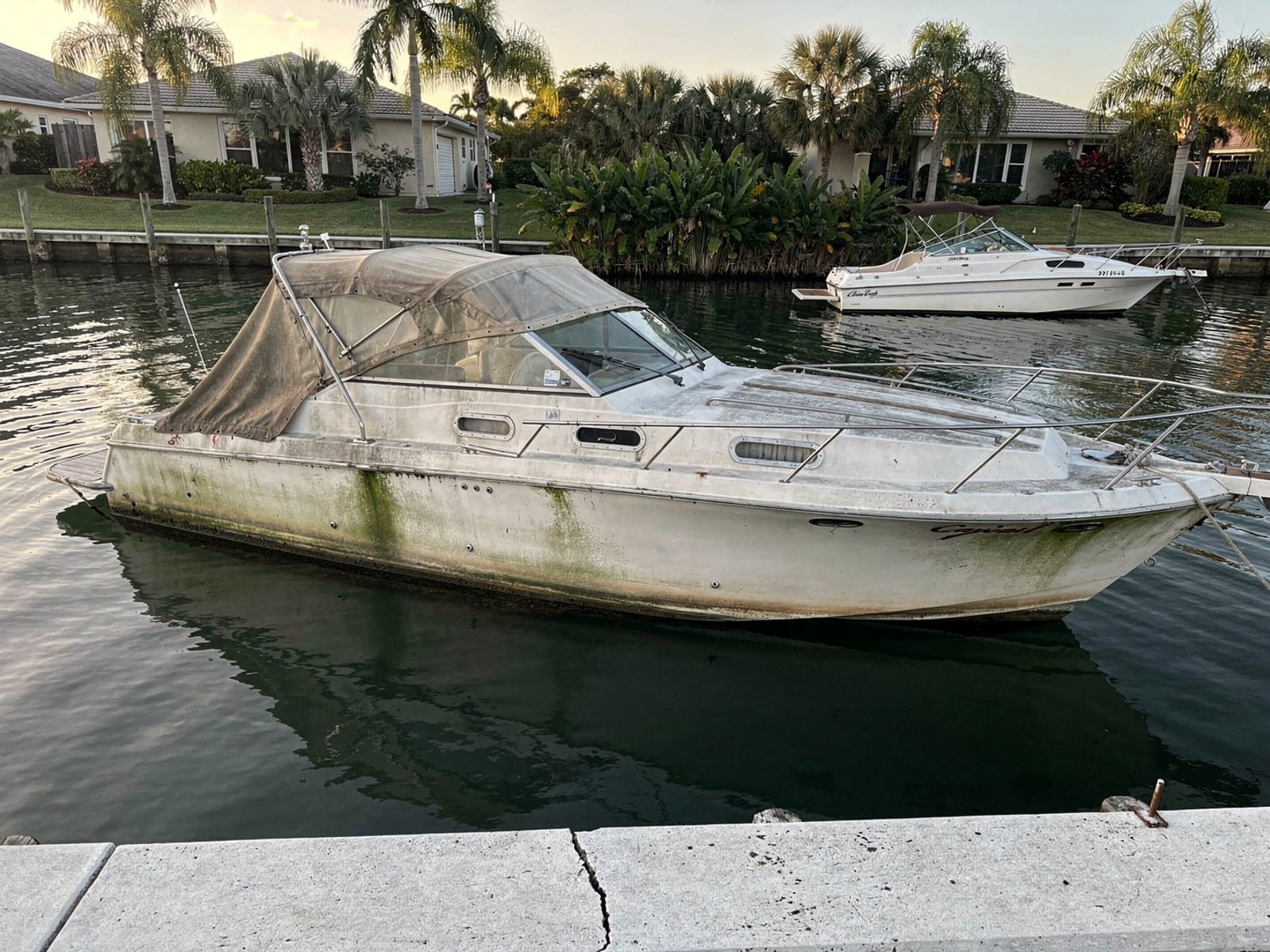 Sunken boat recovery in Plantation, FL: before Sunken 23 ft Chris-Craft Cavalier in a canal by the seawall in Plantation, FL