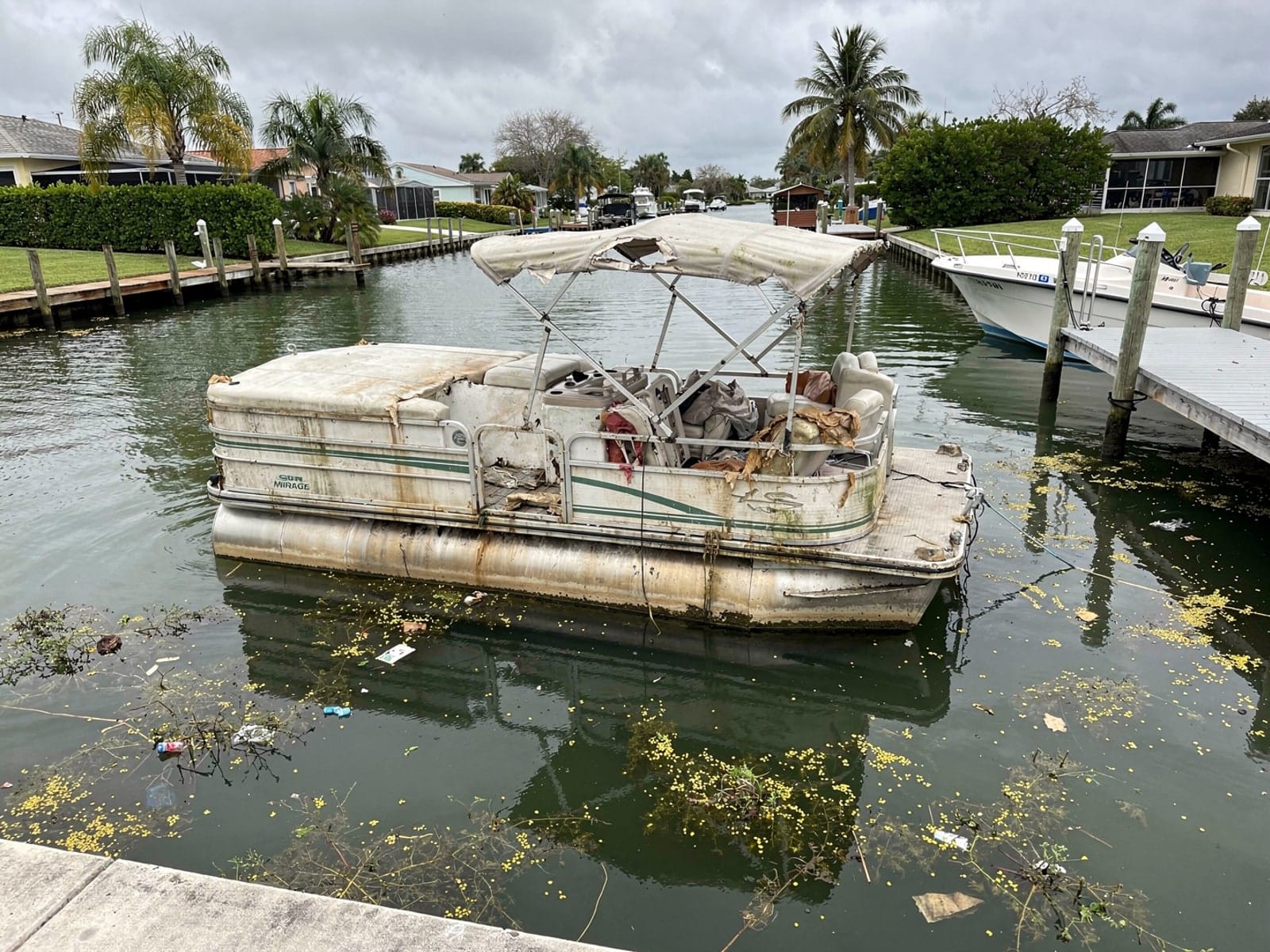Sunken 20 ft Sylvan Mirage 20 in a canal by the seawall in Westview, FL