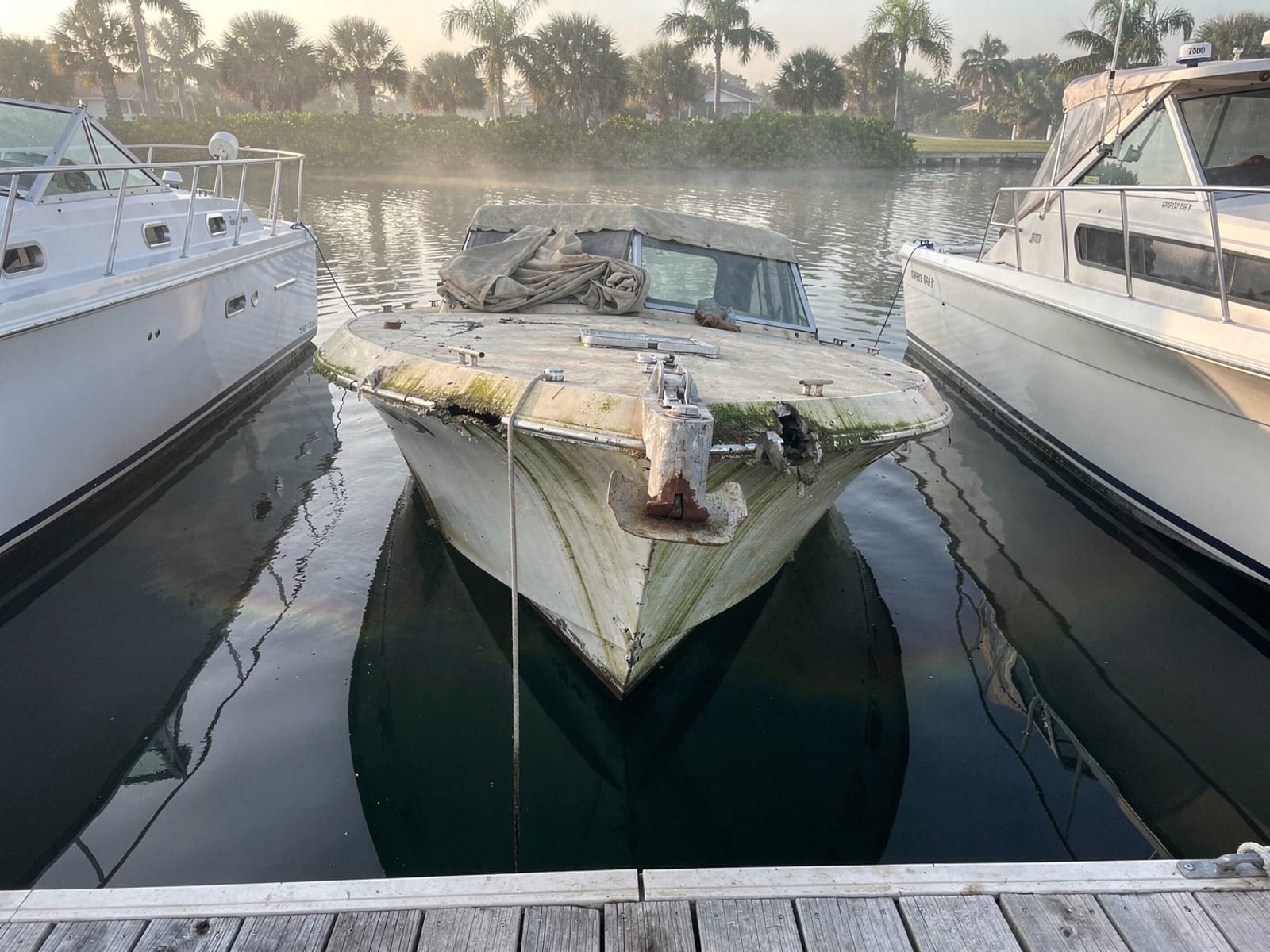 Sunken 23 ft Chris-Craft Cavalier in a marina slip in Titusville, FL