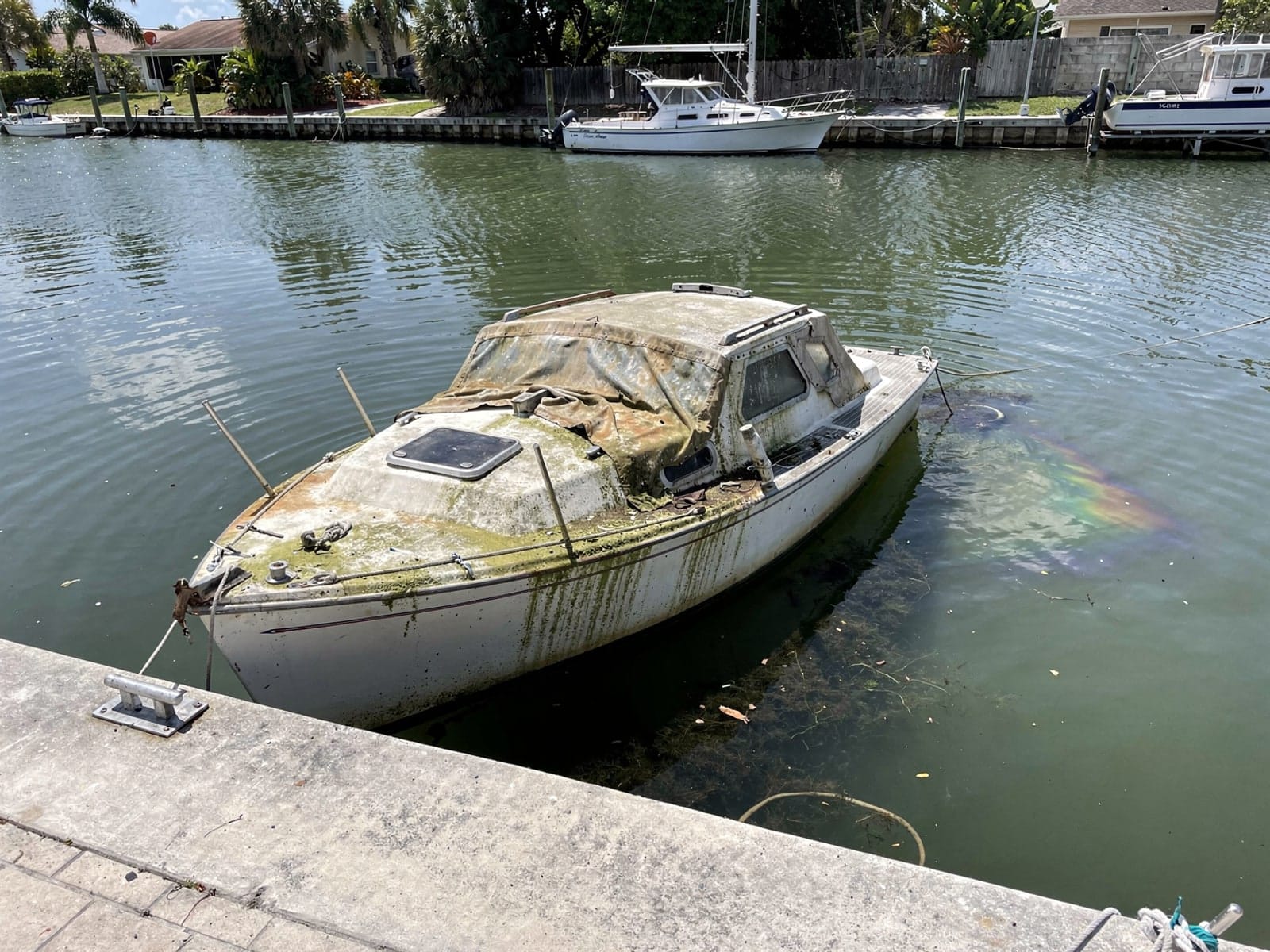 Sunken boat recovery in Miami Beach, FL: before Sunken 26 ft Pearson 26 in a canal by the seawall in Miami Beach, FL
