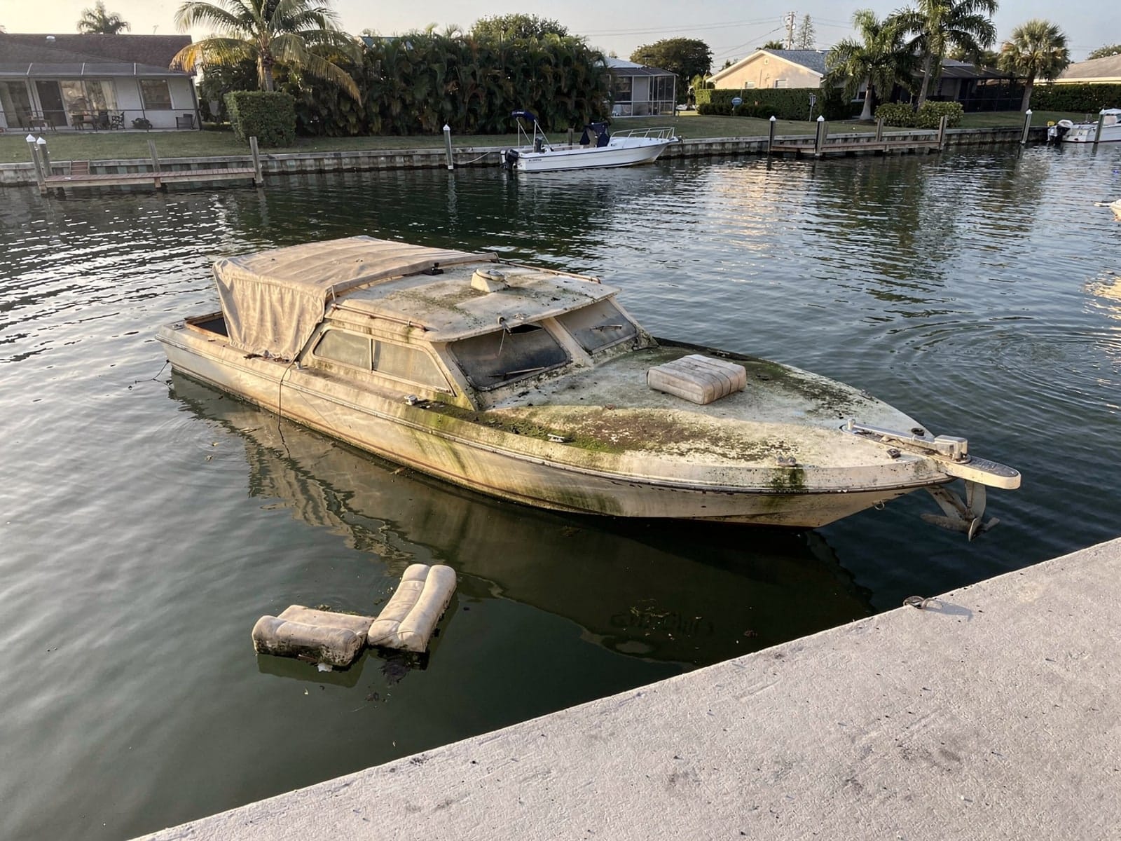 Sunken 23 ft Chris-Craft Cavalier in a canal by the seawall in Wright, FL